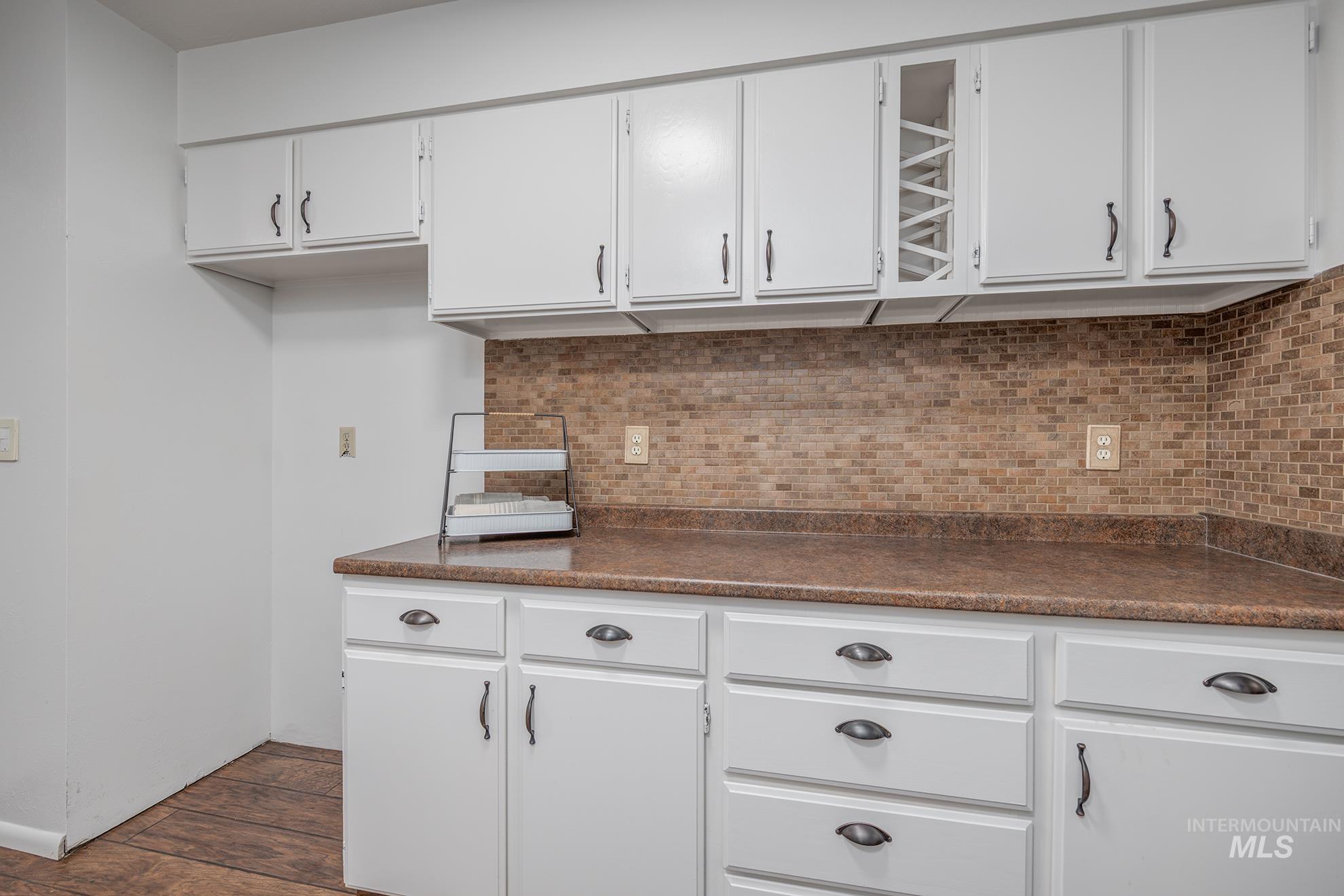 Kitchen featuring white cabinets, dark countertops, and tasteful backsplash