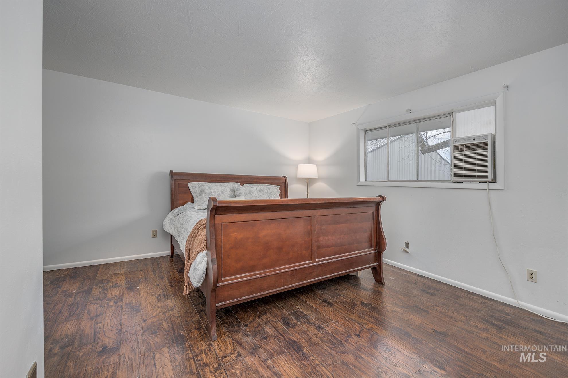 Bedroom with dark wood-style flooring and baseboards