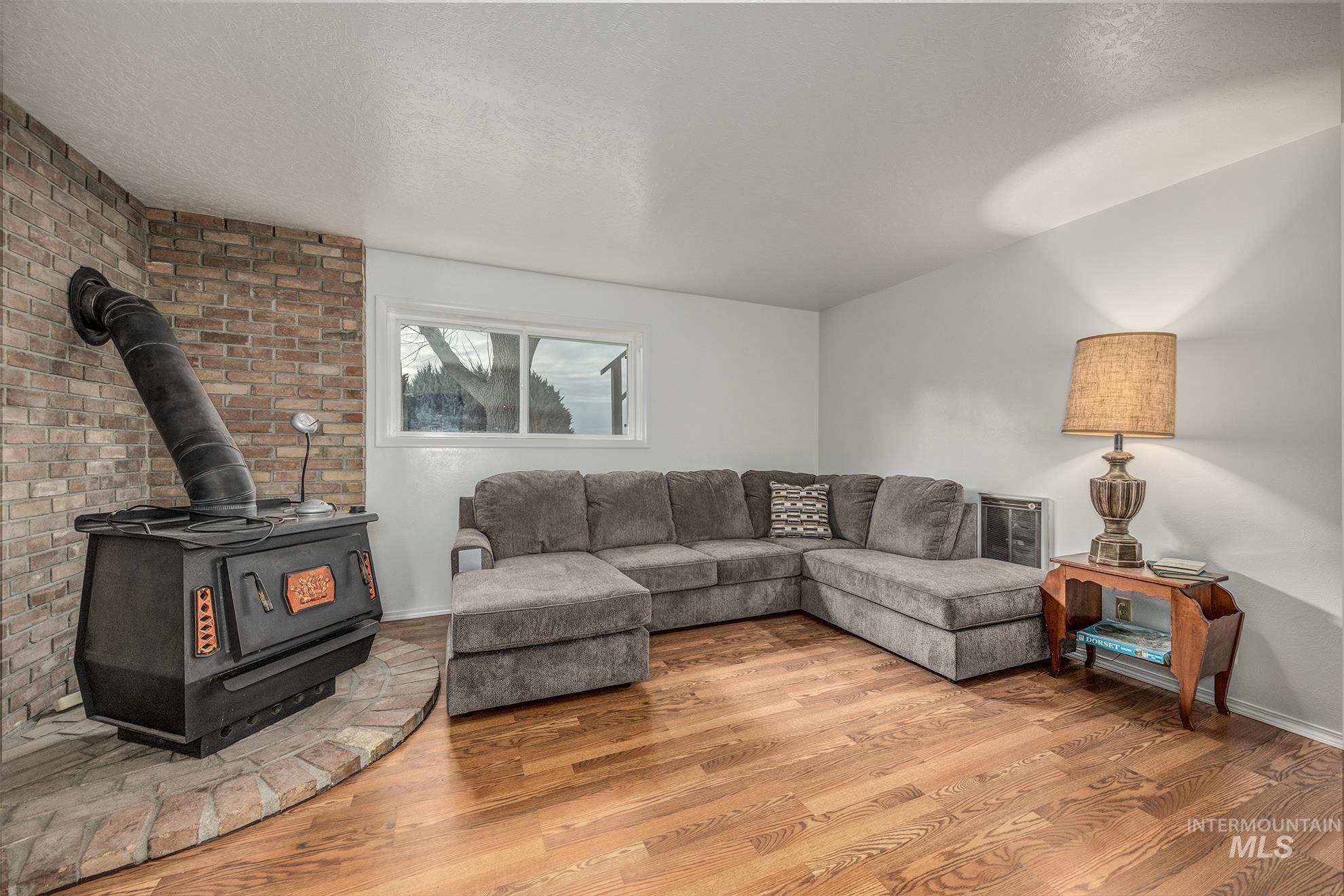 Living area featuring a wood stove, wood finished floors, and a textured ceiling