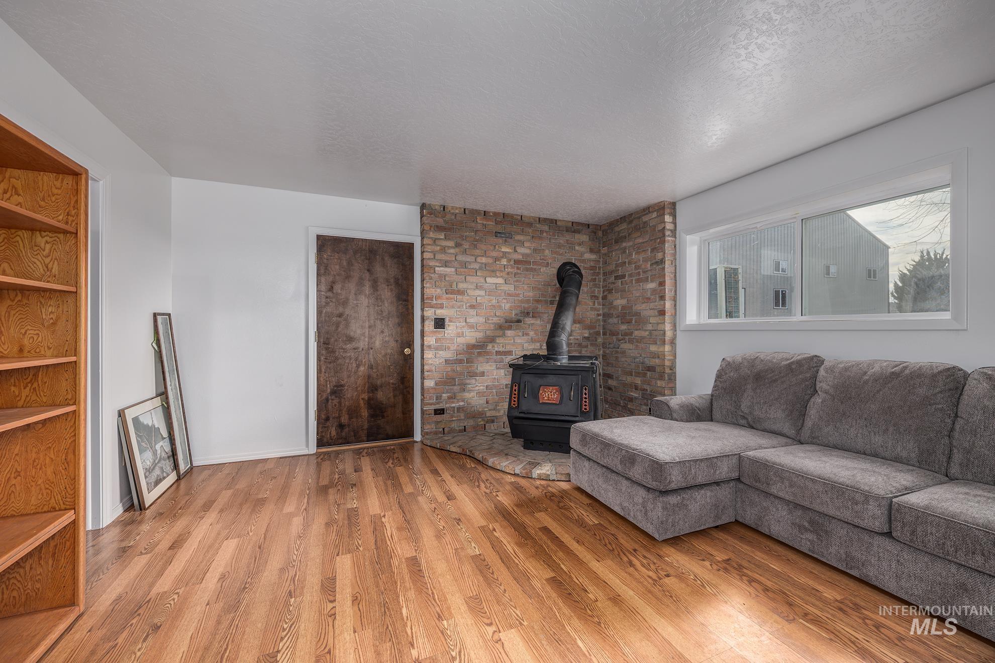 Living room with a wood stove, a textured ceiling, and light wood finished floors