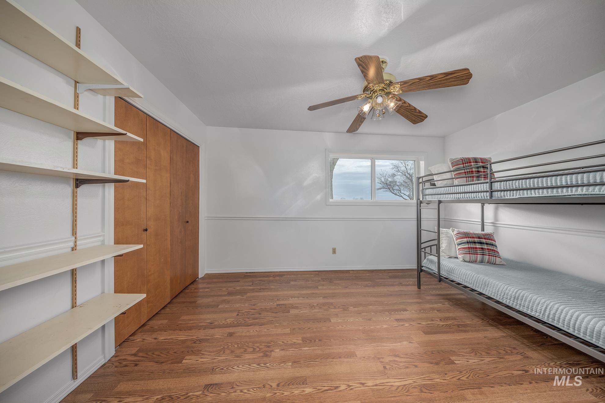 Unfurnished bedroom featuring light wood finished floors, a closet, and ceiling fan