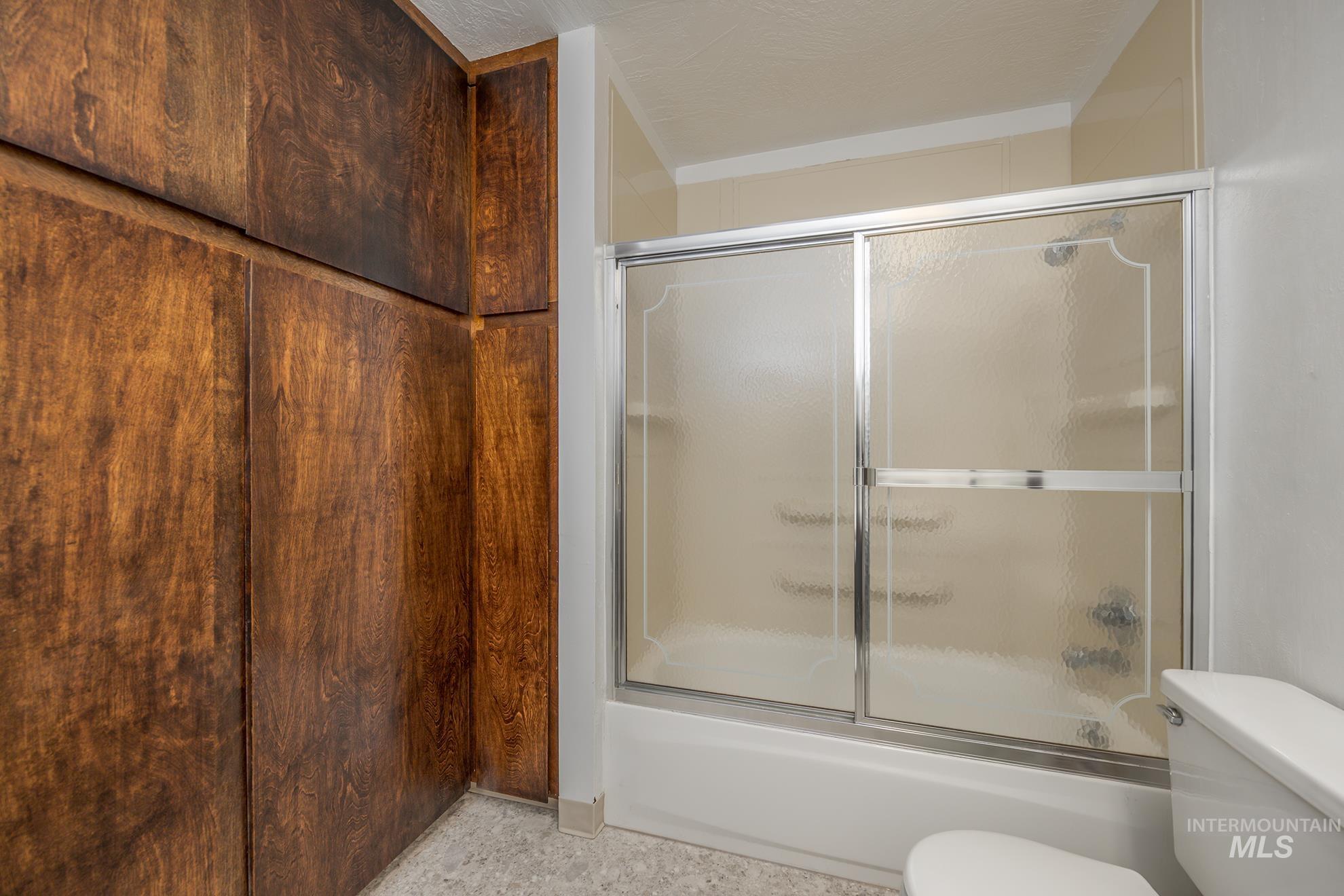 Full bathroom featuring enclosed tub / shower combo and toilet