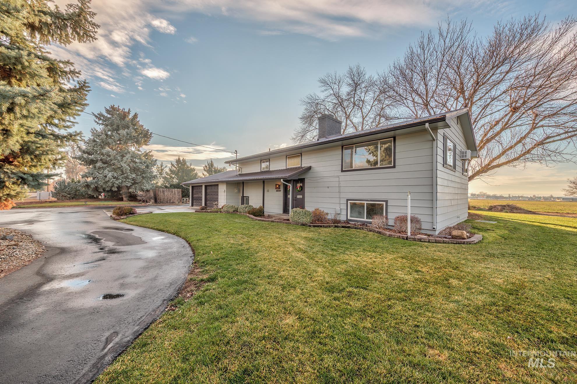 View of front of house featuring a chimney, asphalt driveway, a front lawn, covered porch, and a garage