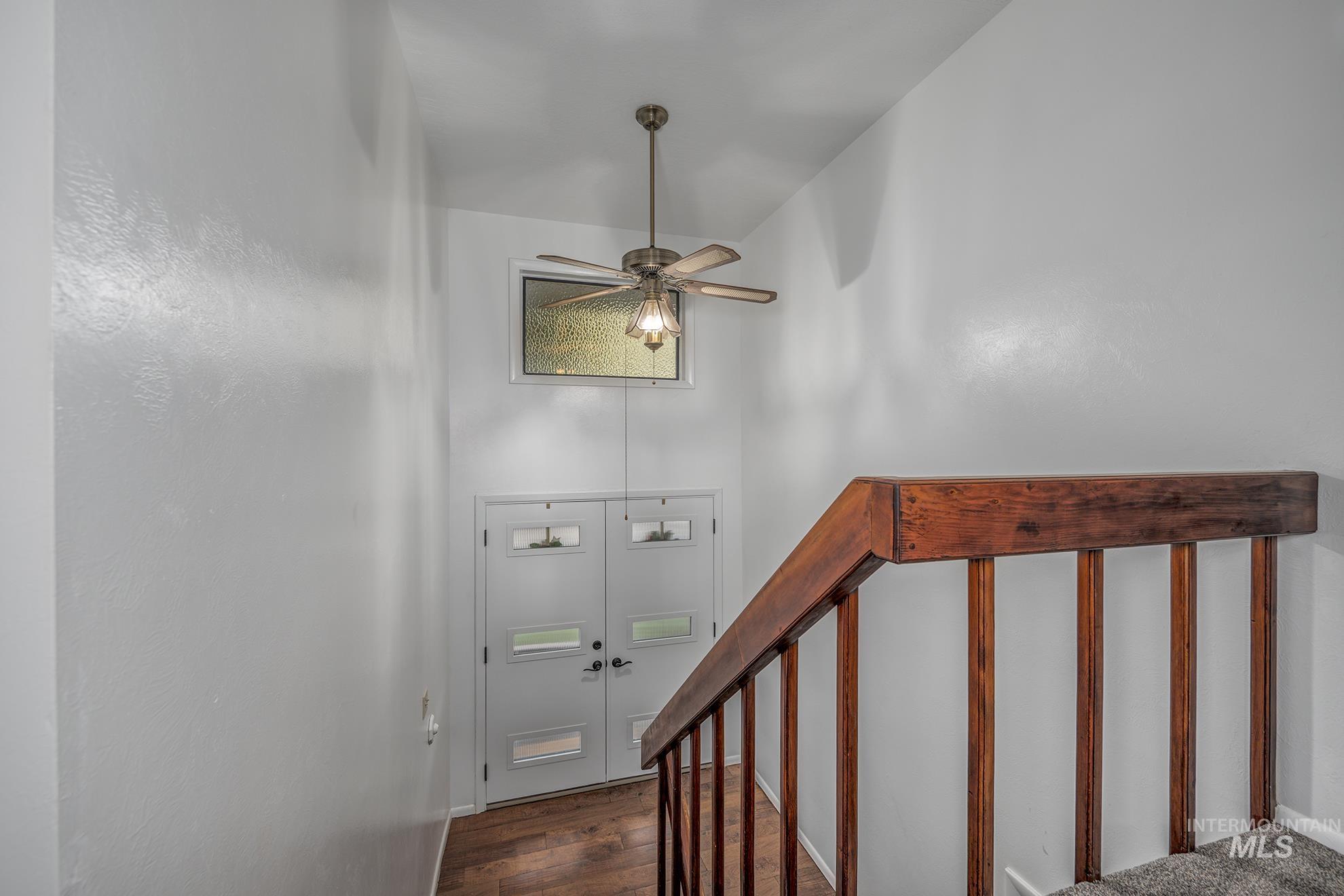 Stairway featuring a towering ceiling, hardwood / wood-style floors, and a ceiling fan