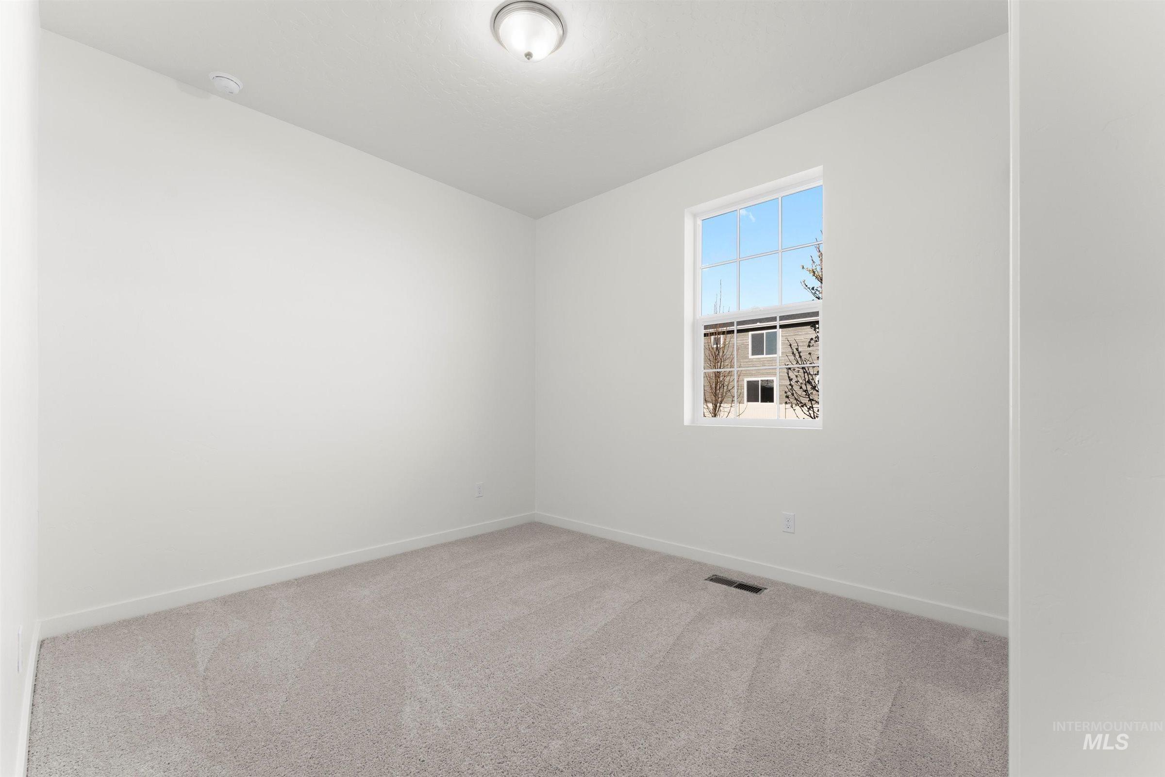 Spare room featuring light colored carpet and baseboards