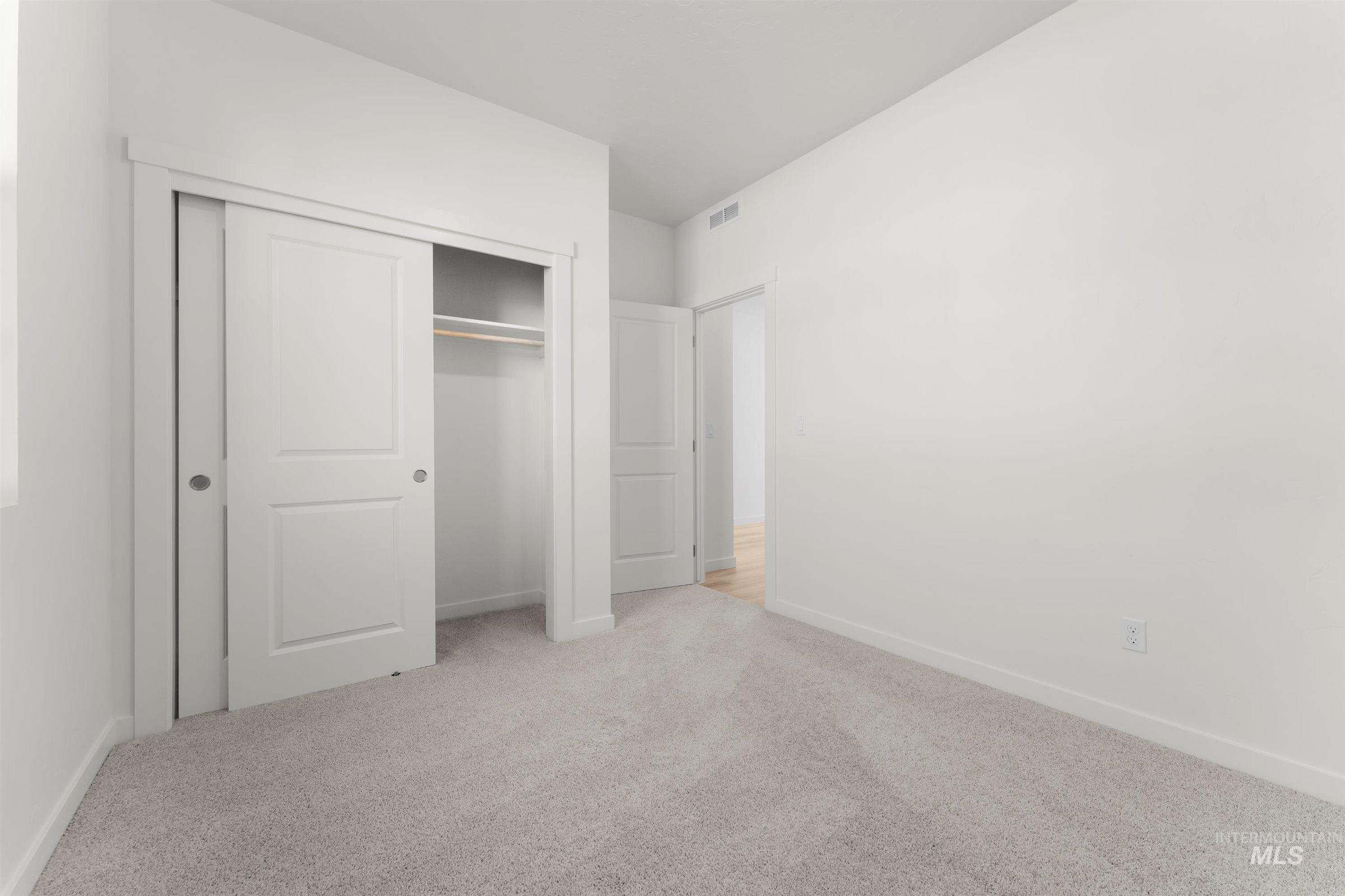 Unfurnished bedroom featuring light carpet and a closet