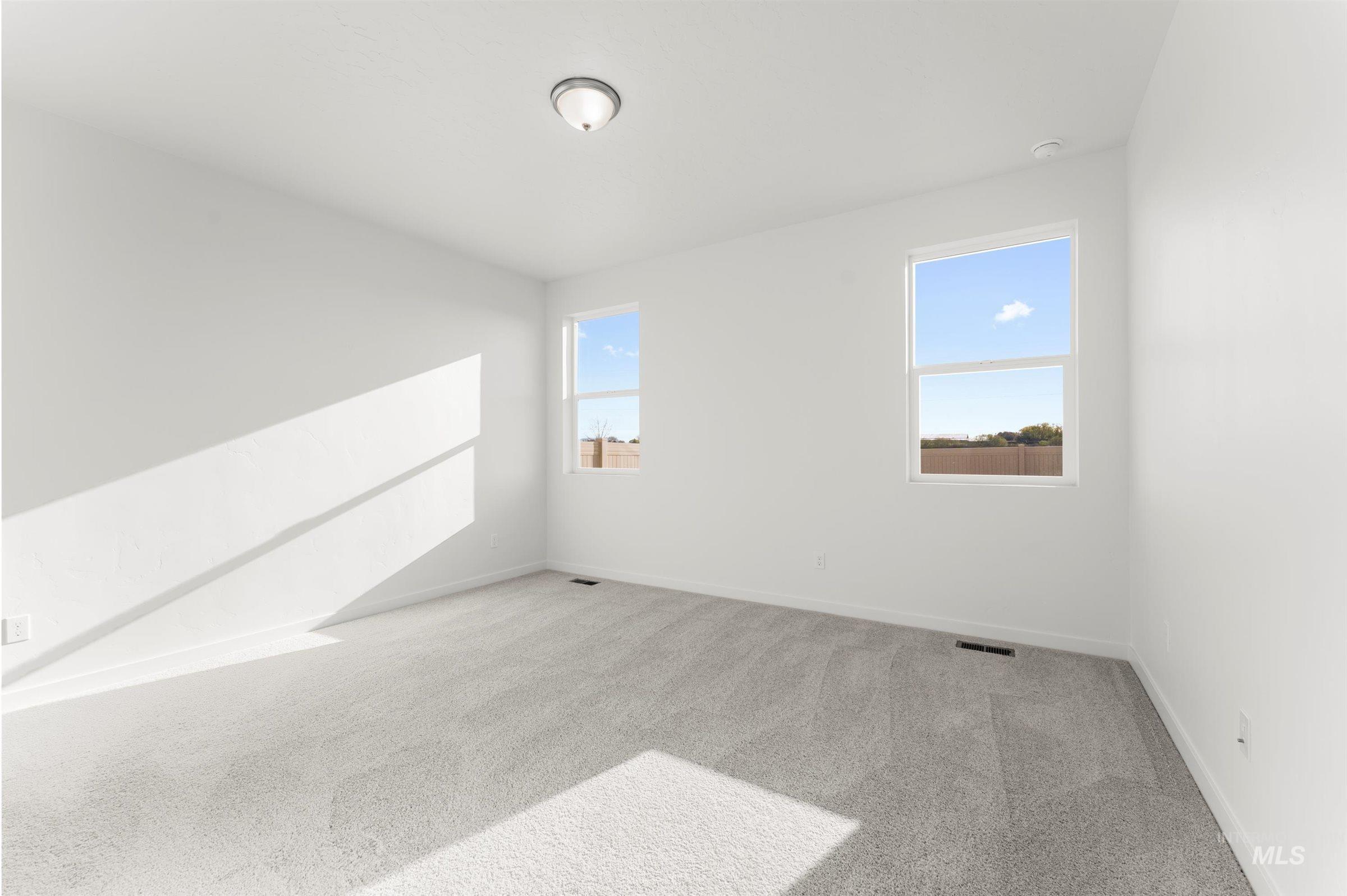 Empty room with light colored carpet and baseboards