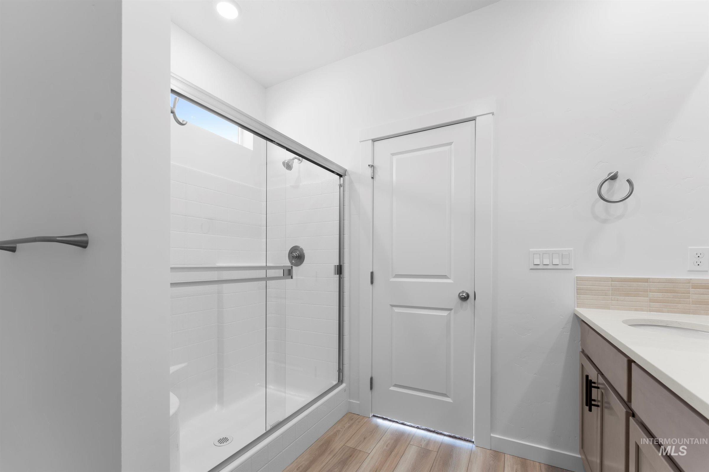 Full bath featuring a shower stall, vanity, and light wood-style flooring