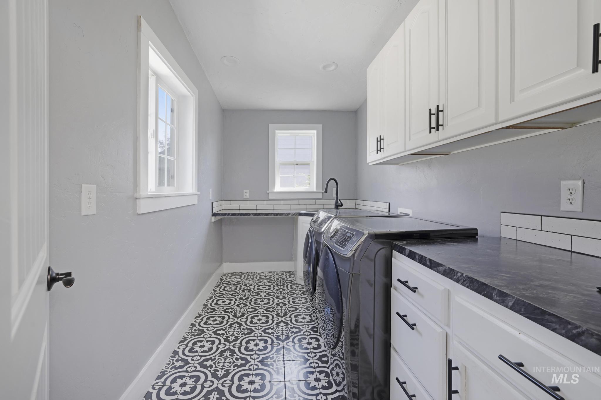Washroom with separate washer and dryer, cabinet space, and tile patterned flooring