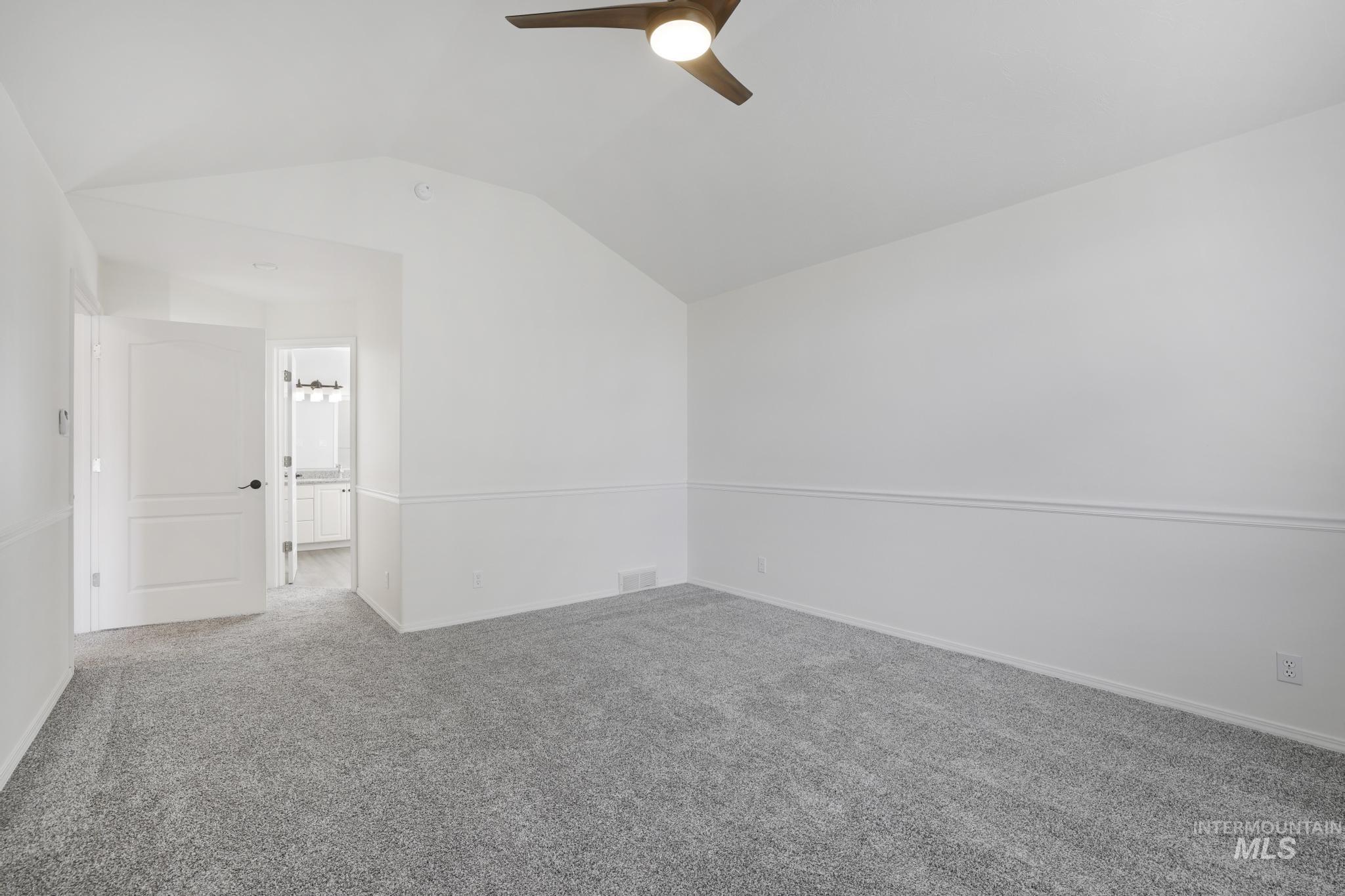 Spare room with lofted ceiling, carpet, and a ceiling fan