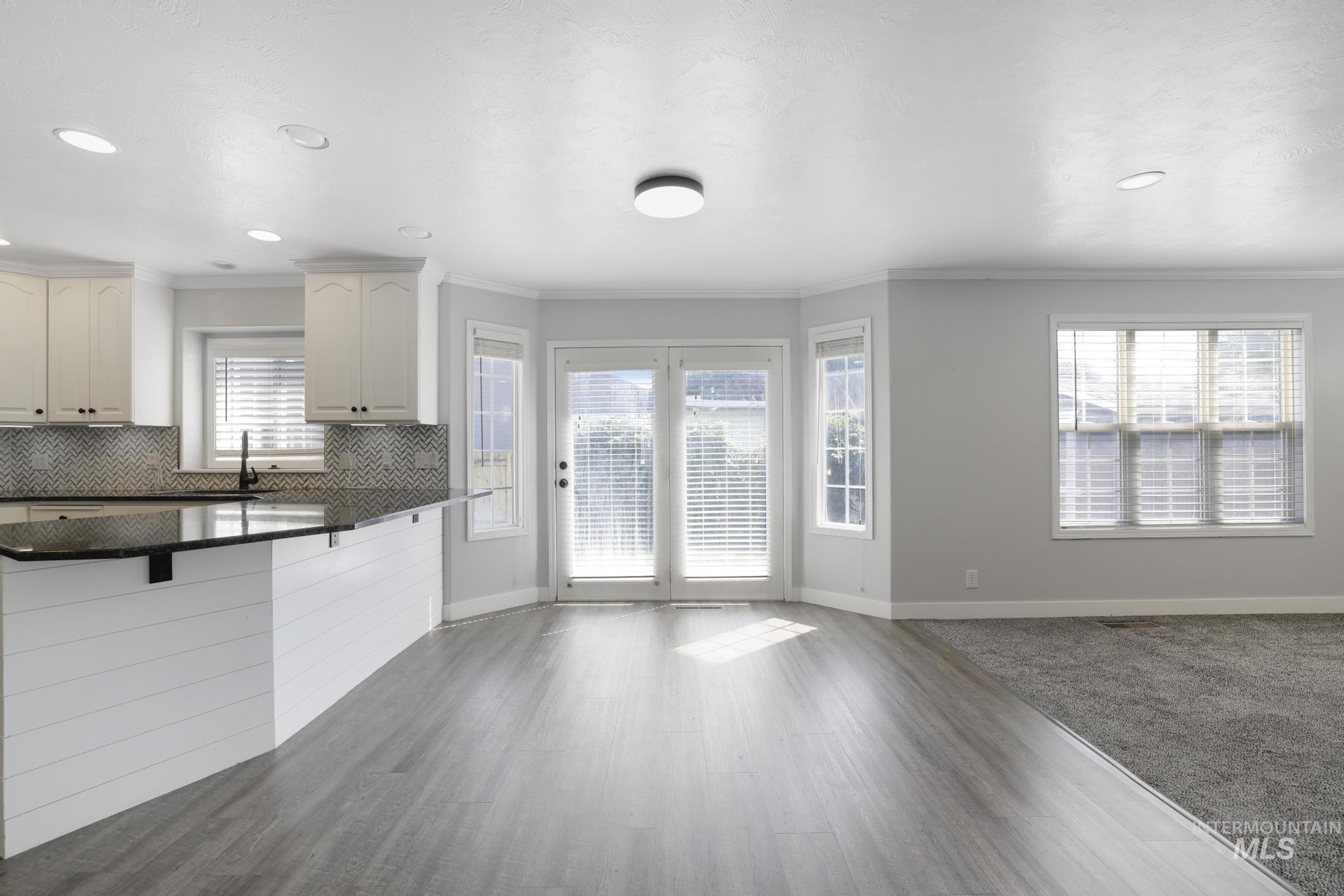 Kitchen featuring crown molding, tasteful backsplash, open floor plan, dark stone countertops, and a kitchen breakfast bar