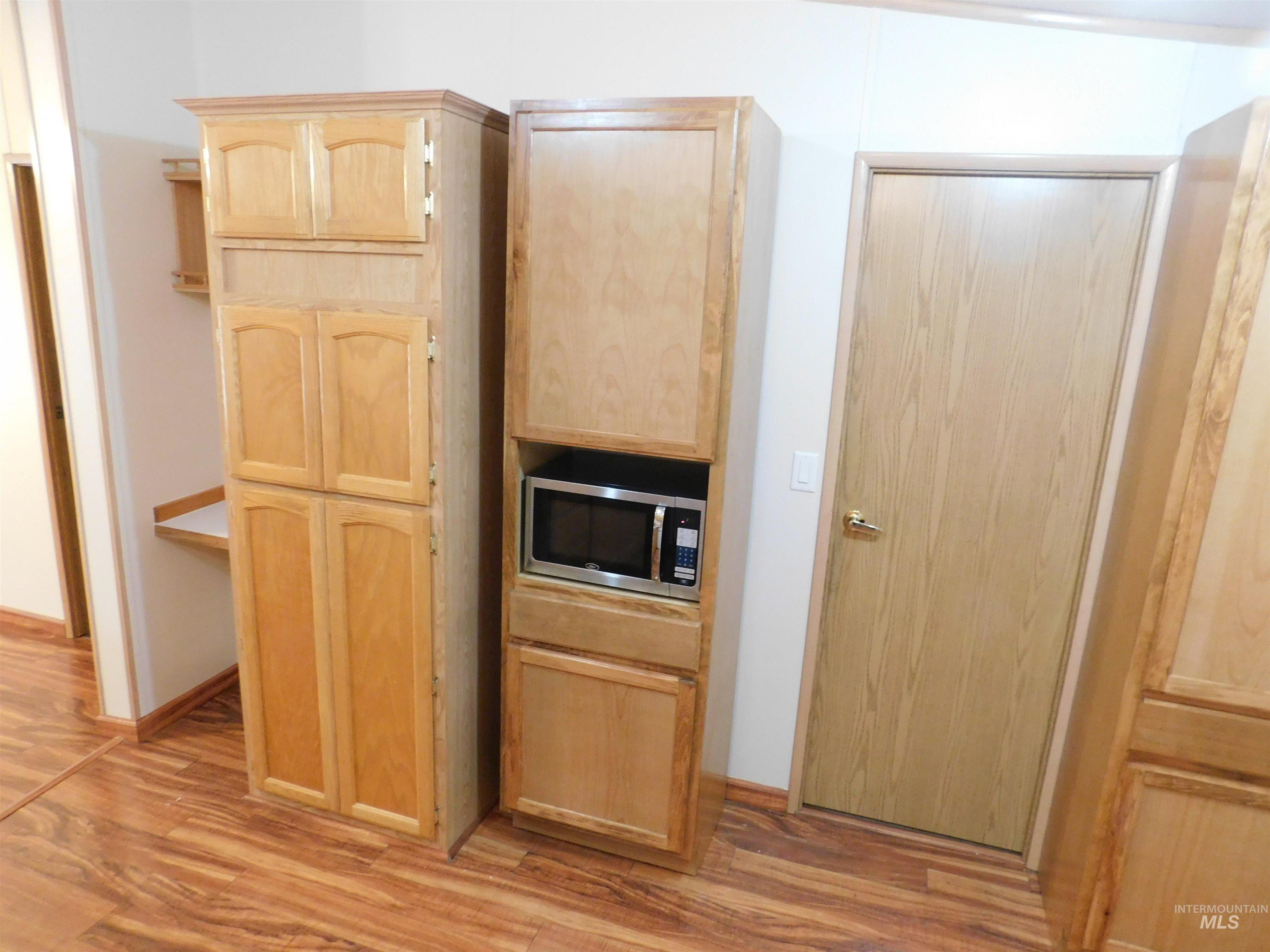 Kitchen with light brown cabinetry, light wood finished floors, and stainless steel microwave