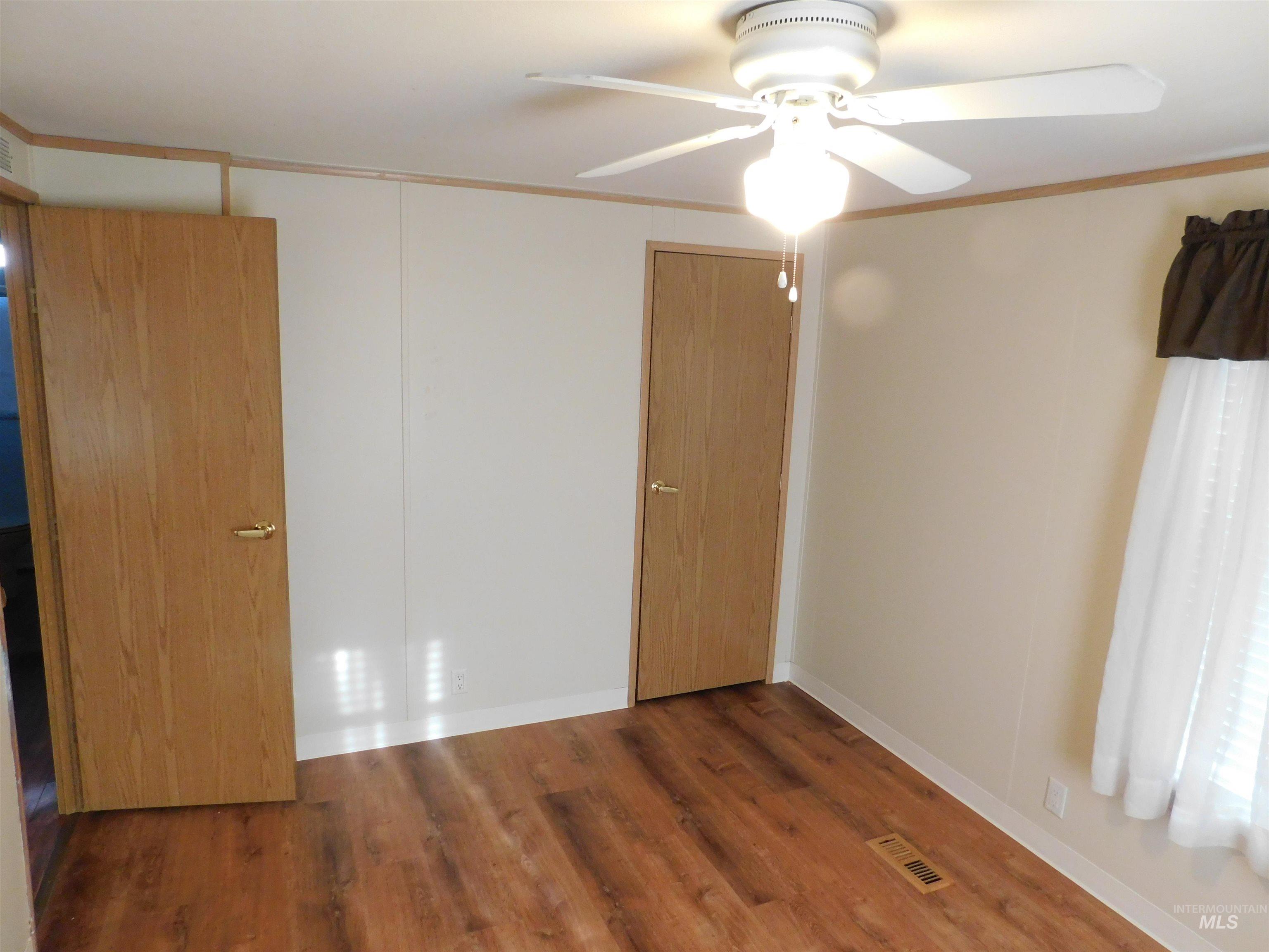 Unfurnished bedroom featuring a ceiling fan, dark wood-type flooring, and ornamental molding
