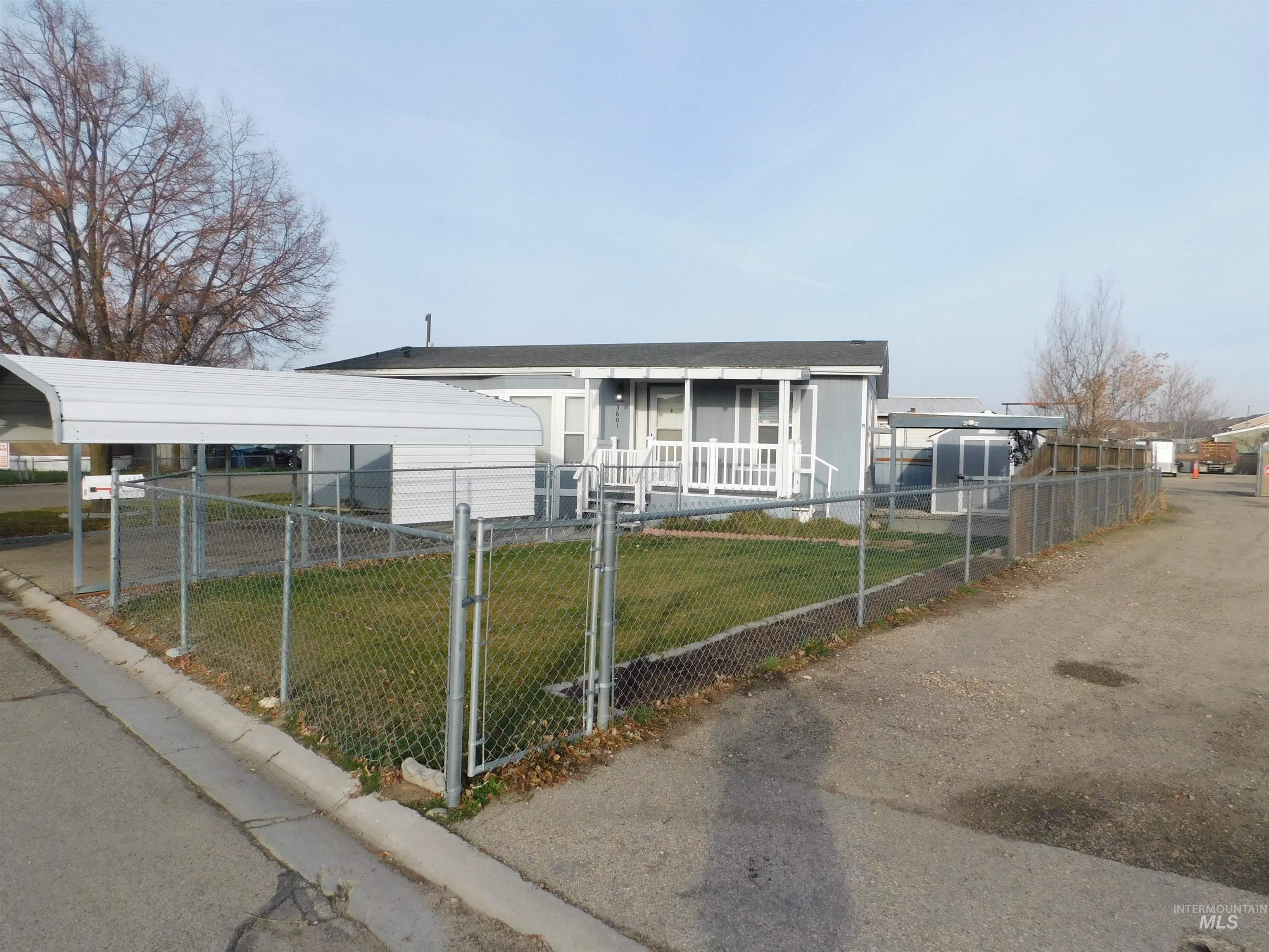 View of front of property featuring a gate, a fenced front yard, covered porch, and a carport