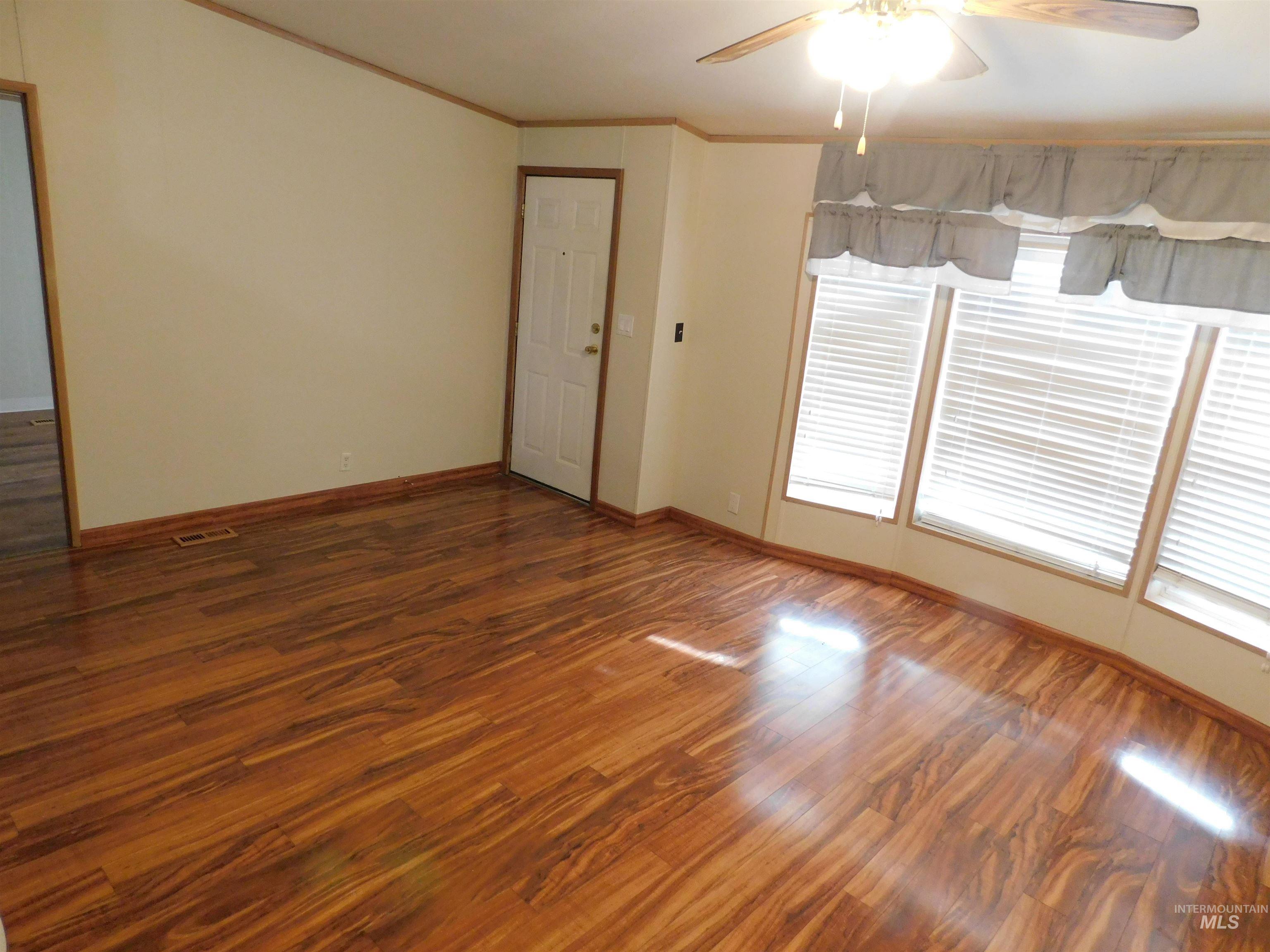 Spare room with a ceiling fan, wood finished floors, and crown molding