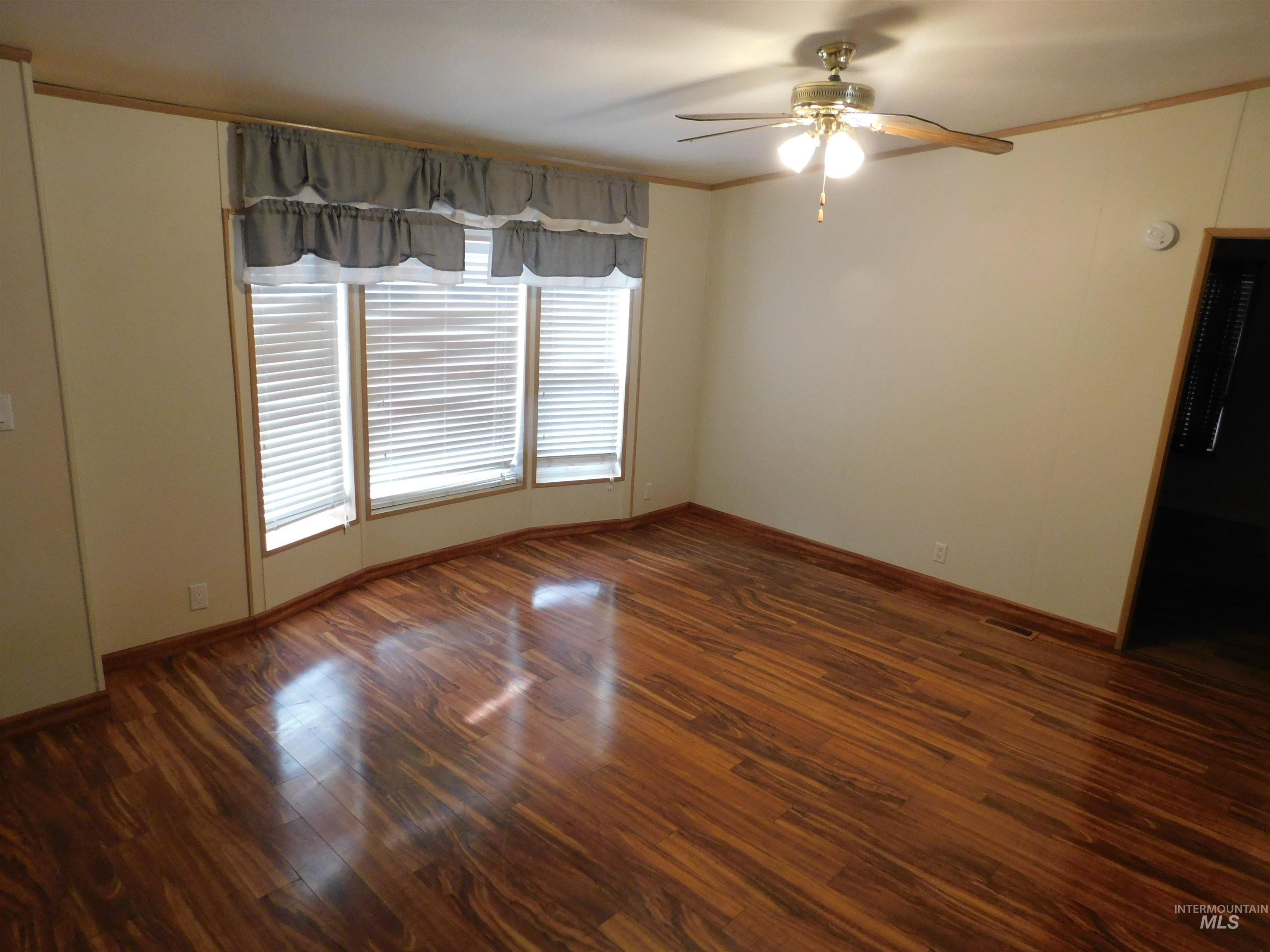 Spare room featuring dark wood-type flooring and ceiling fan