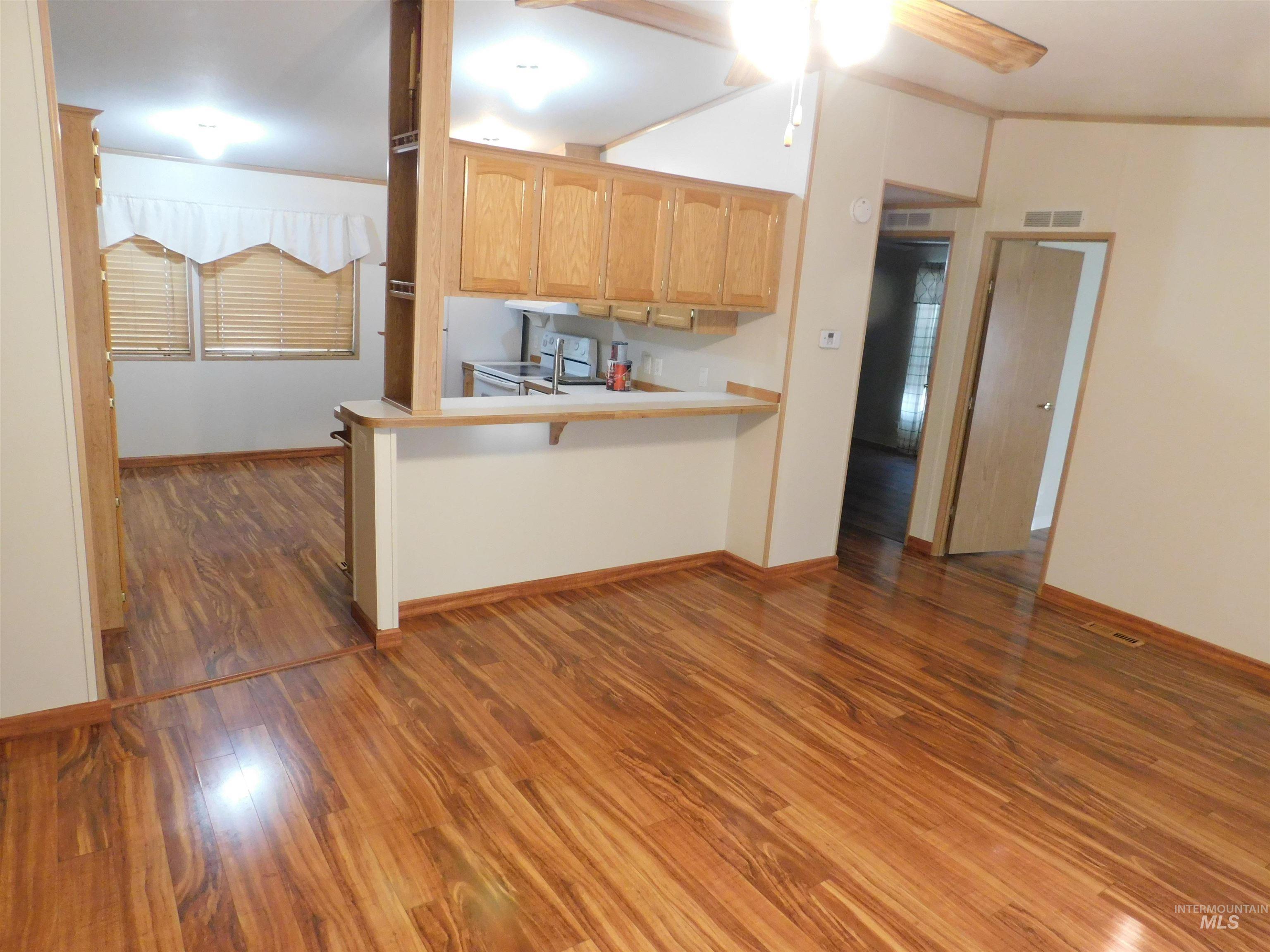 Kitchen with light countertops, dark wood-type flooring, a peninsula, white electric range oven, and crown molding