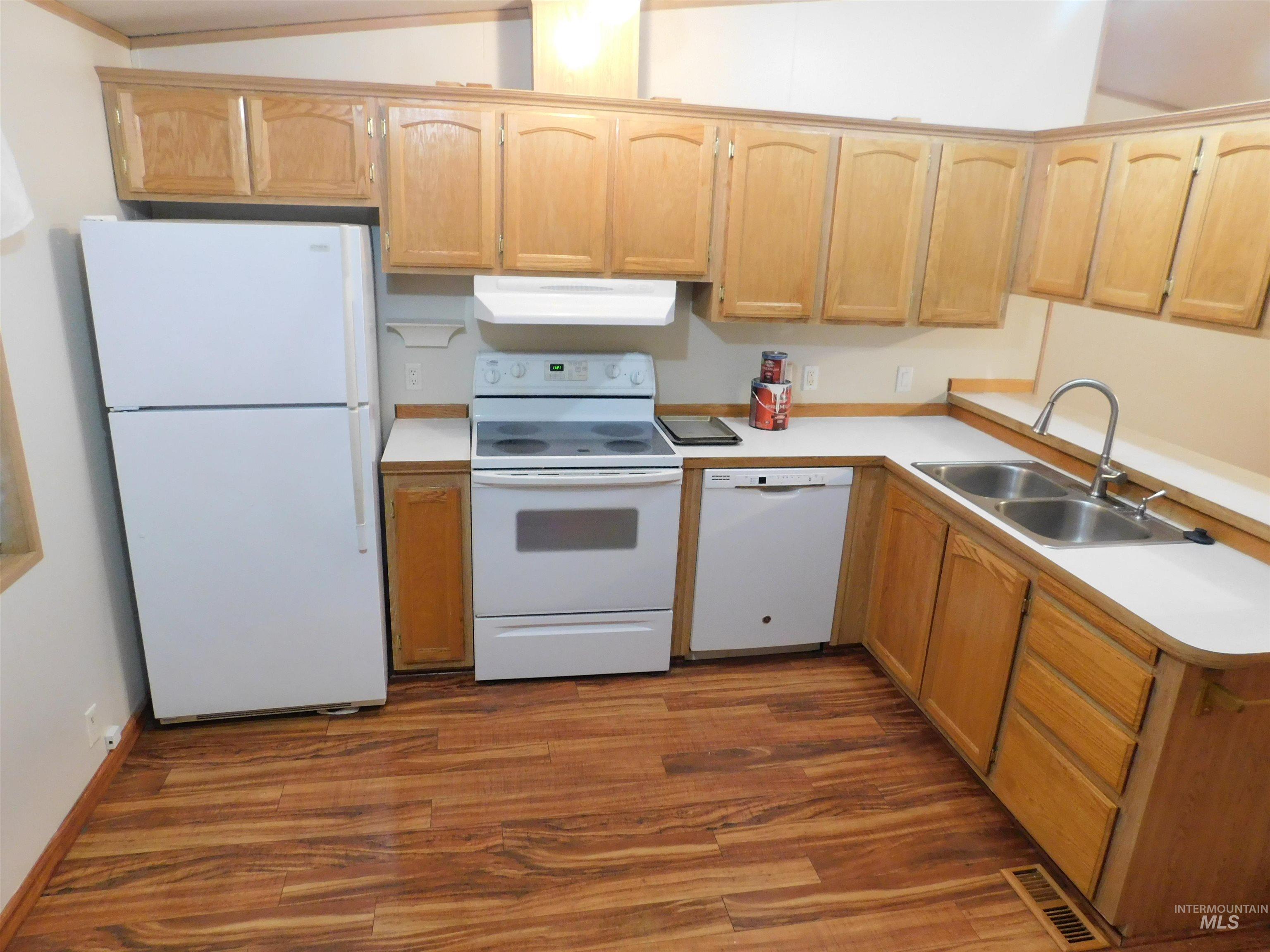 Kitchen featuring white appliances, light countertops, and dark wood-style flooring