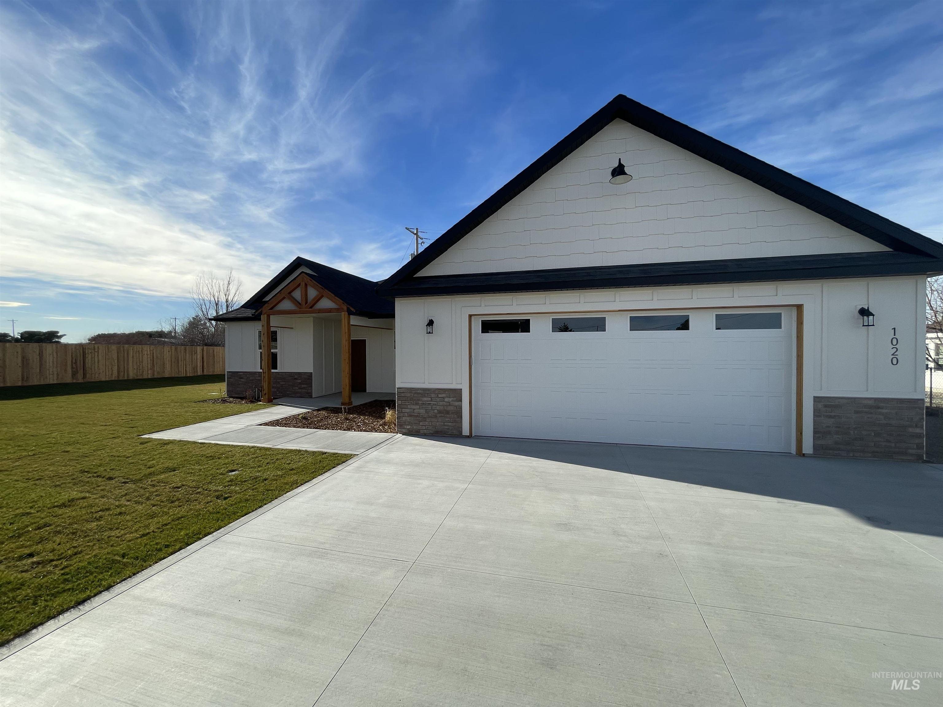 View of front facade featuring stone siding, driveway, a garage, and board and batten siding