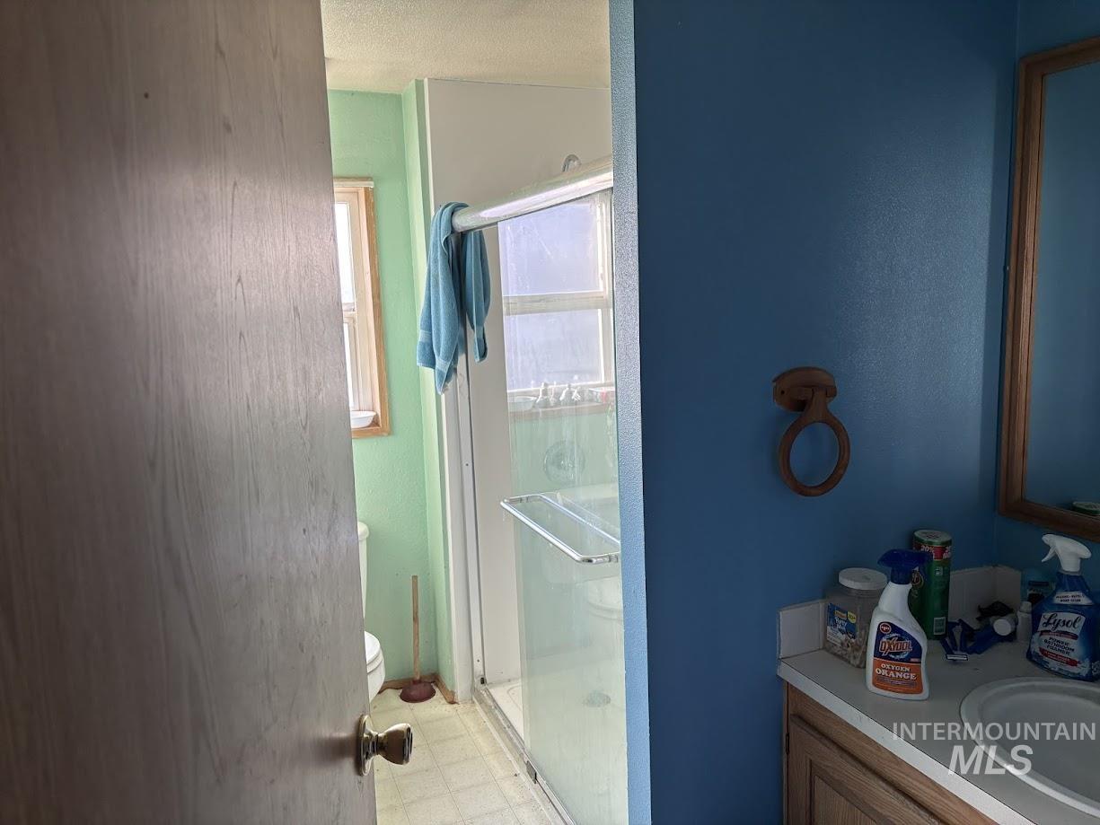 Bathroom featuring vanity, a shower stall, light flooring, washer / clothes dryer, and a textured ceiling