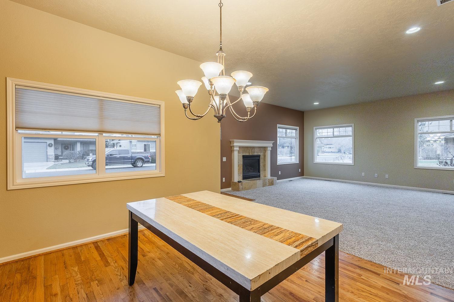 Dining area featuring a tile fireplace, a chandelier, light wood-style flooring, and recessed lighting