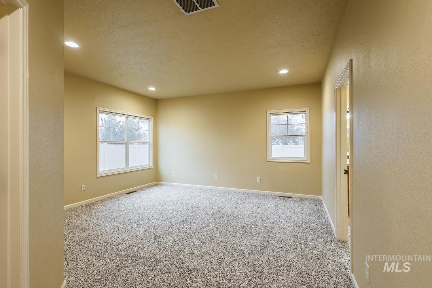 Empty room featuring light colored carpet, recessed lighting, and a textured ceiling