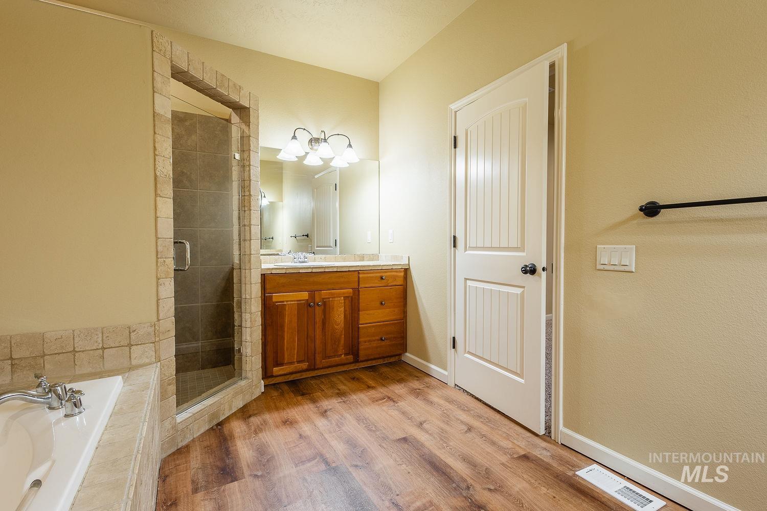 Full bathroom featuring vanity, a garden tub, a shower stall, and light wood finished floors