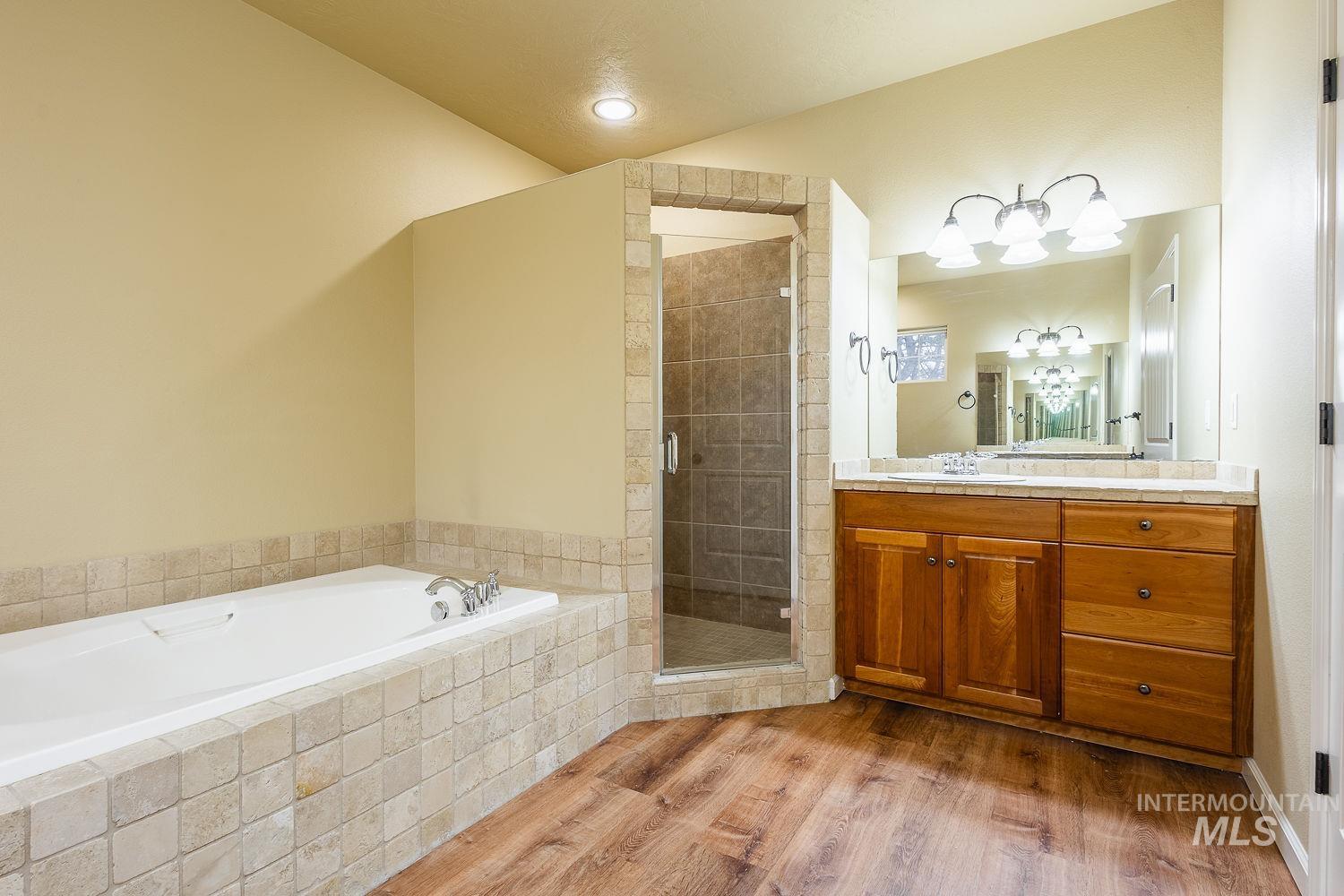 Bathroom featuring light wood finished floors, vanity, a bath, and a shower stall