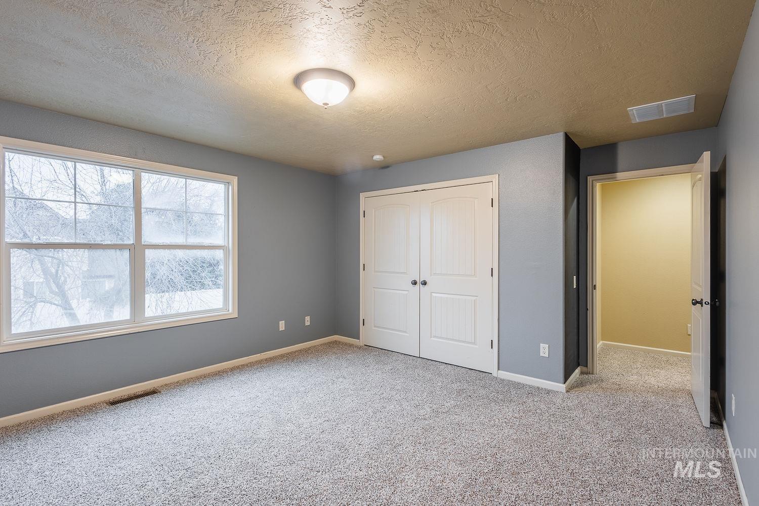 Unfurnished bedroom with a textured ceiling, carpet, and a closet