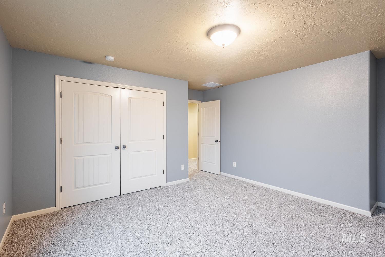 Unfurnished bedroom featuring carpet floors, a textured ceiling, and a closet