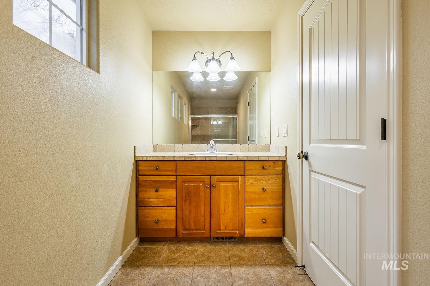 Bathroom featuring vanity, a shower stall, a textured wall, and light tile patterned floors