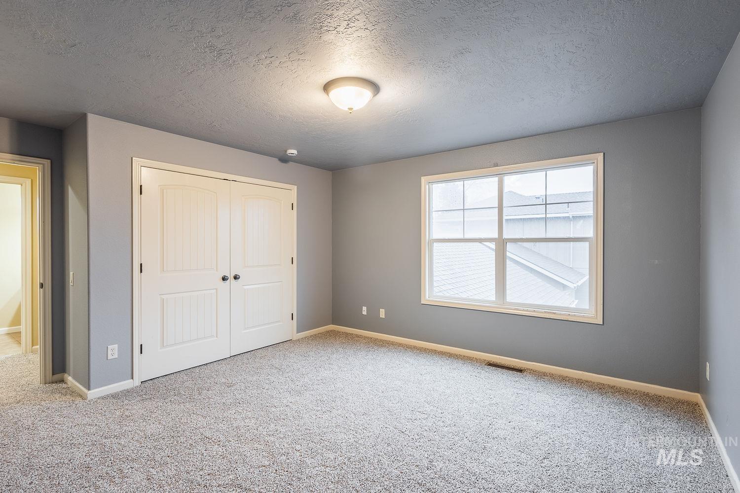 Unfurnished bedroom featuring a textured ceiling, a closet, and carpet floors