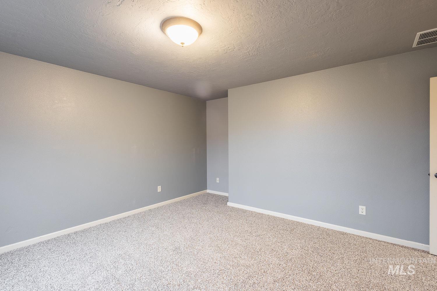 Carpeted empty room with baseboards and a textured ceiling