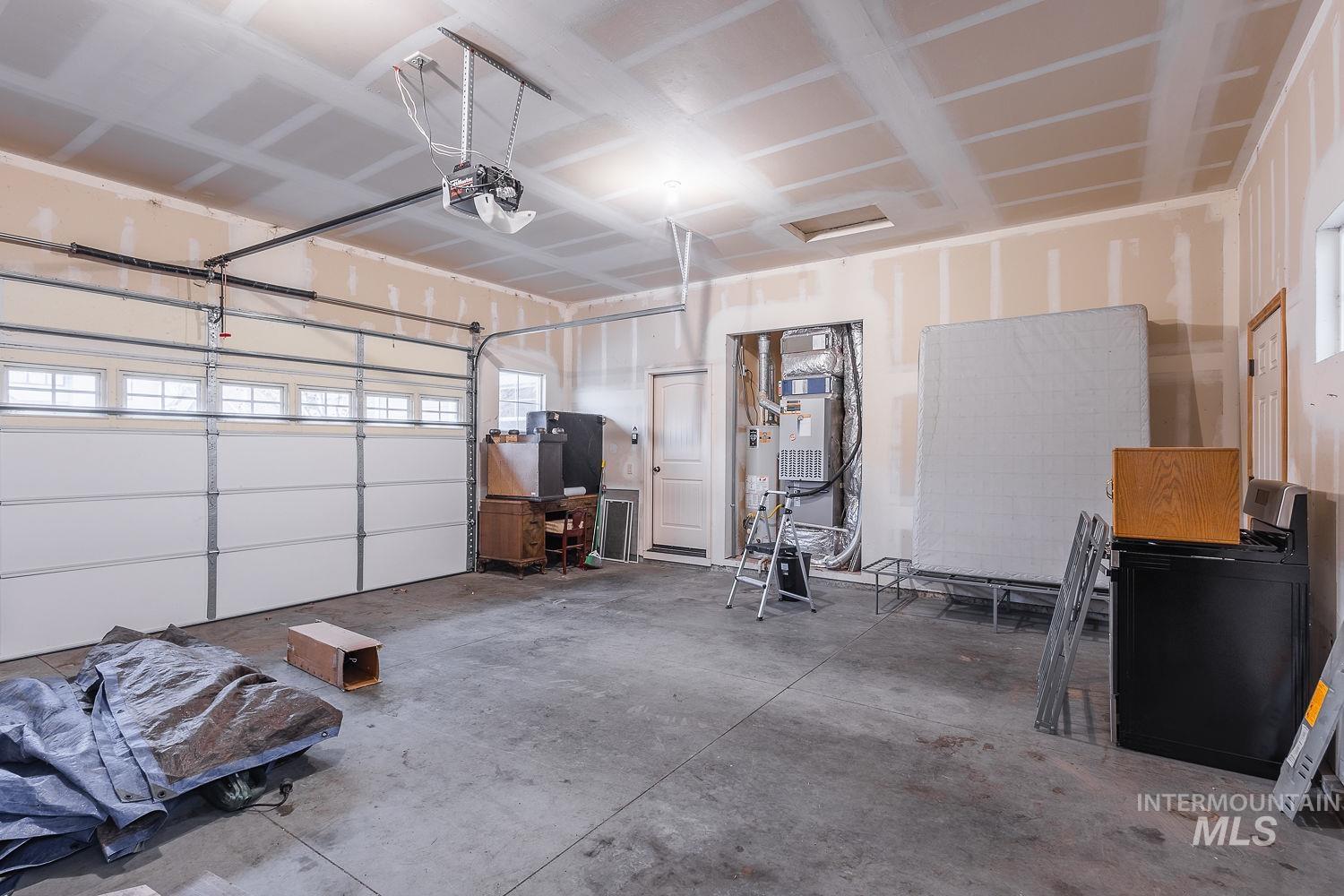 Garage featuring a garage door opener, heating unit, and gas water heater