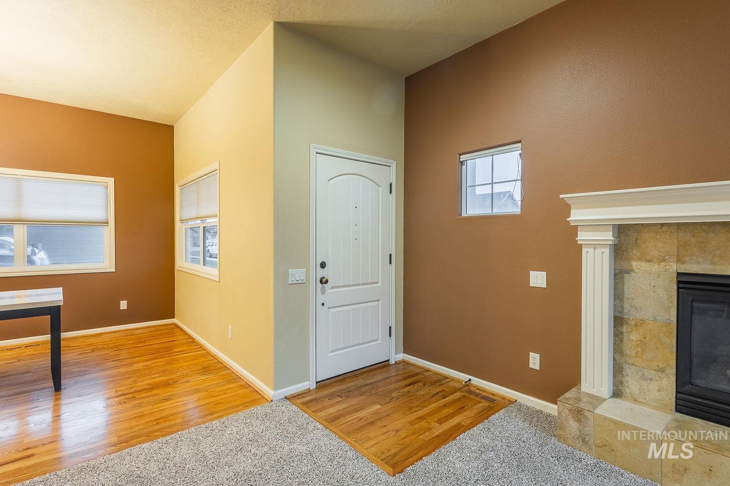 Entrance foyer featuring light wood-style floors, a tiled fireplace, and light carpet