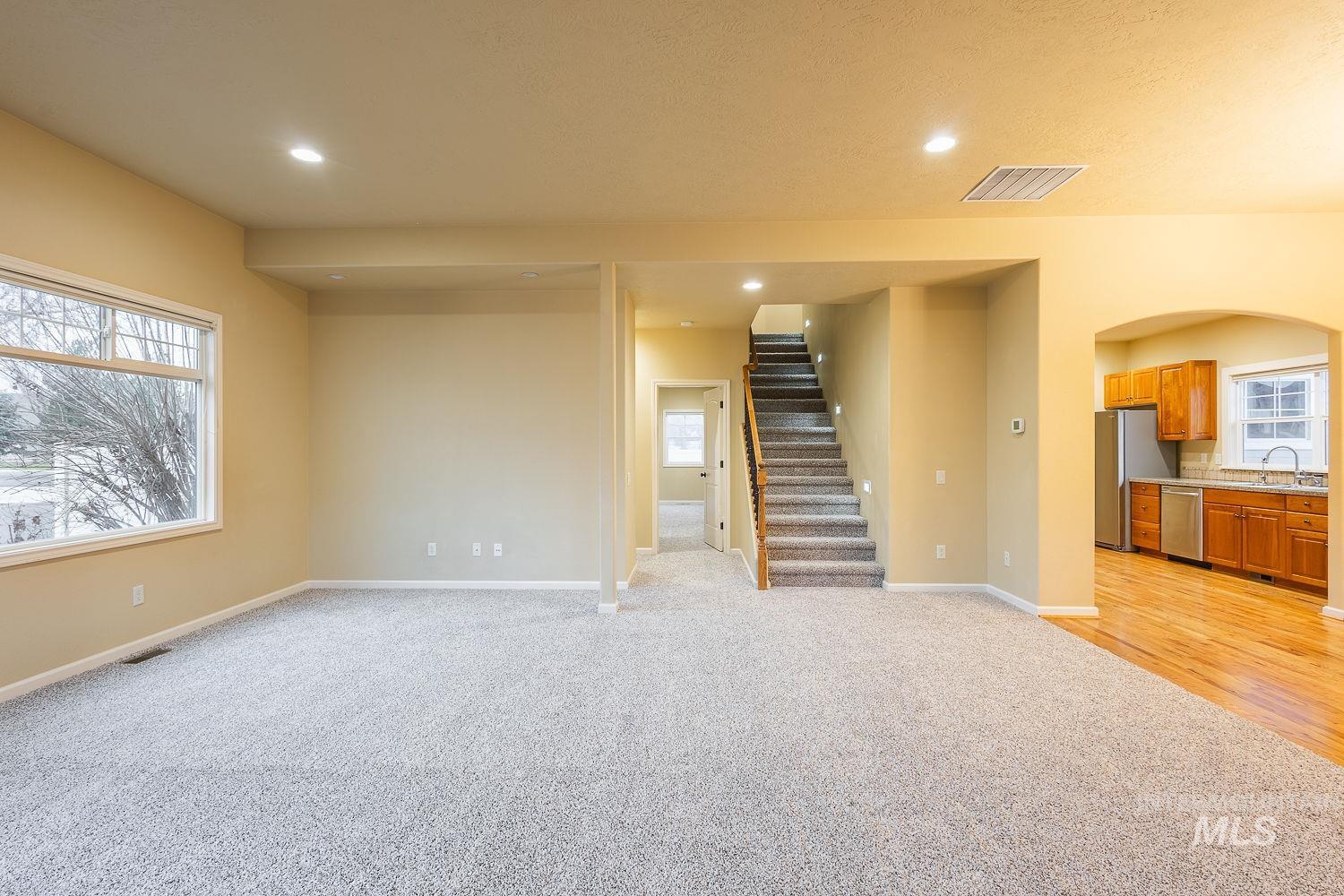 Below grade area with light carpet, stairway, arched walkways, and recessed lighting