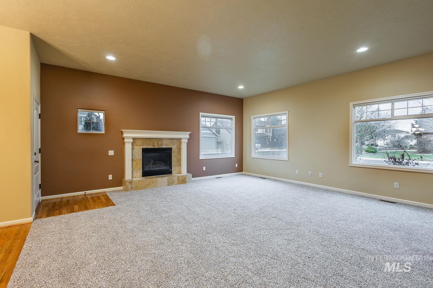 Unfurnished living room featuring a tile fireplace, light carpet, and recessed lighting