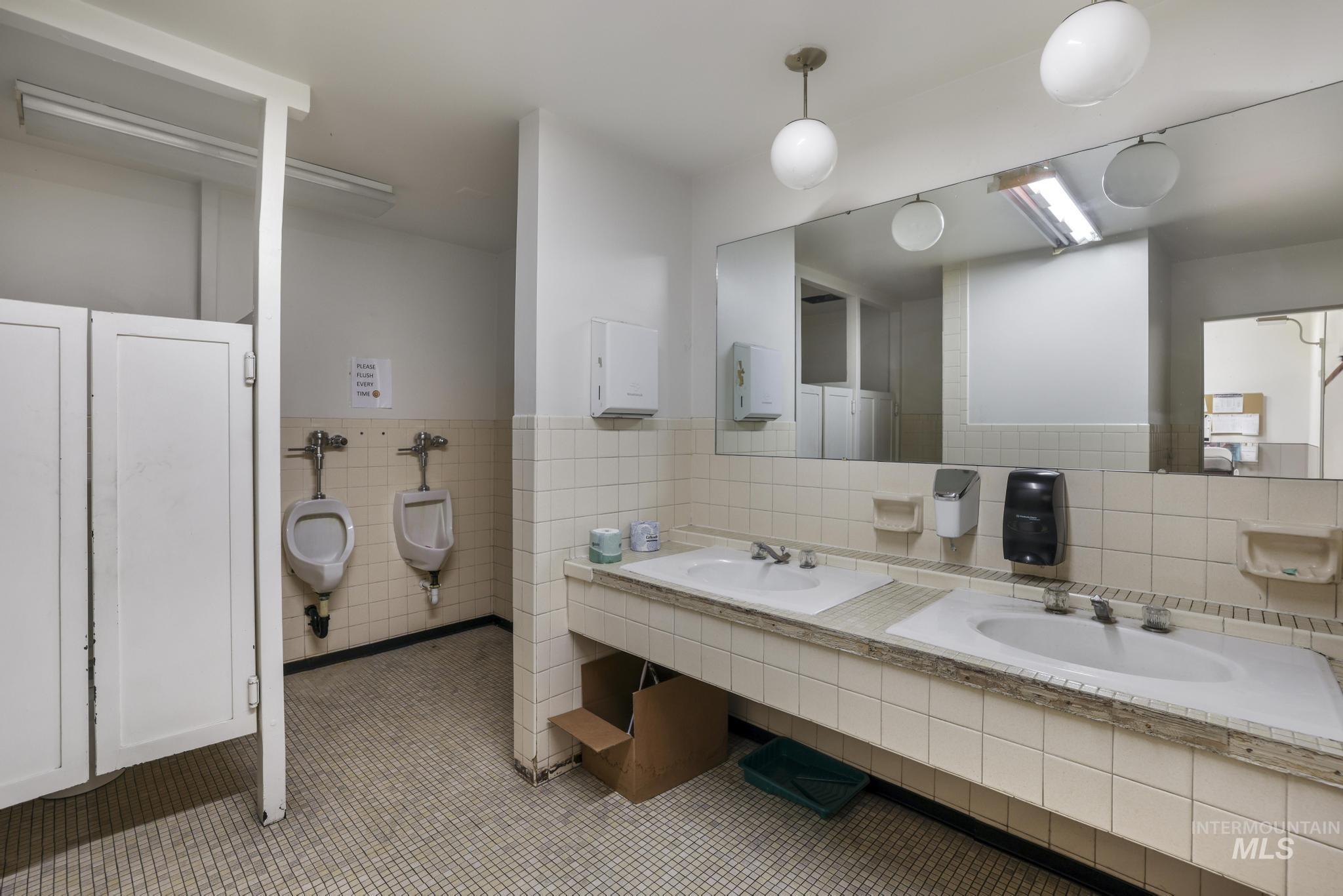 Full bath featuring tile walls, double vanity, and wainscoting