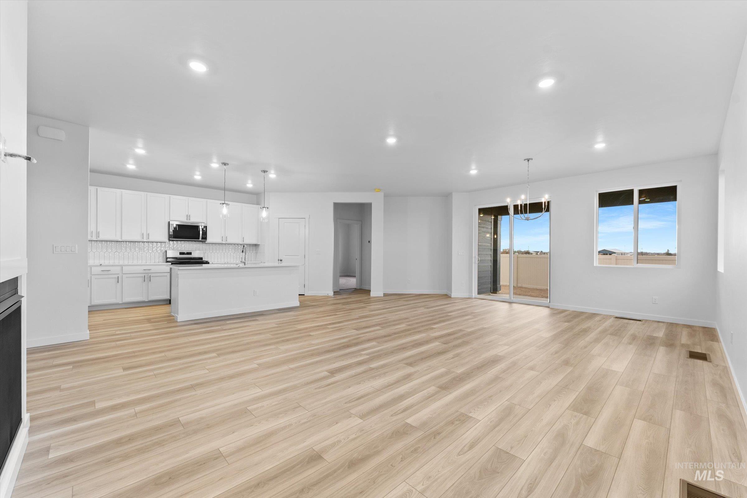 Kitchen with open floor plan, light countertops, white cabinets, hanging light fixtures, and recessed lighting