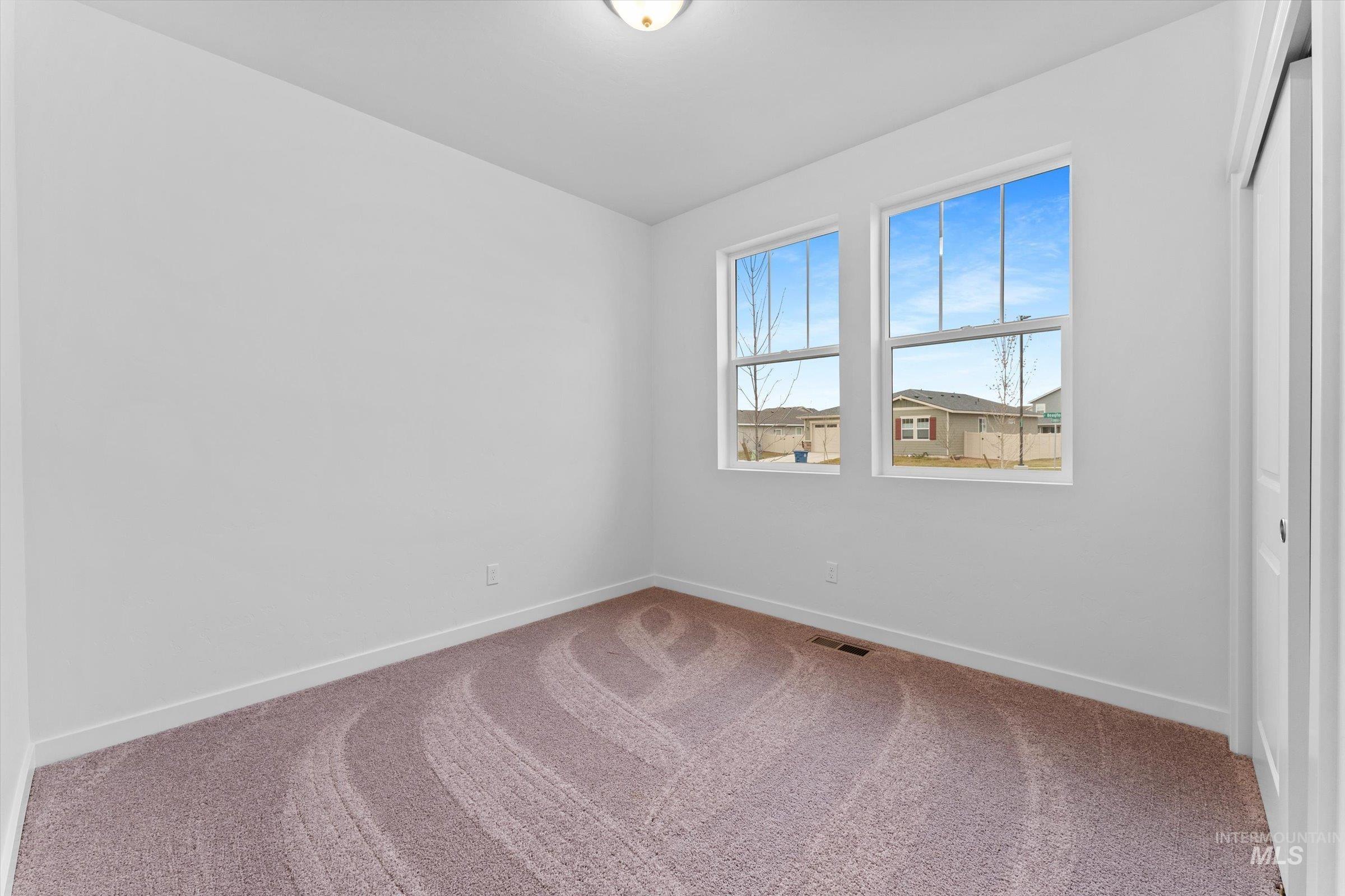 Carpeted empty room featuring baseboards