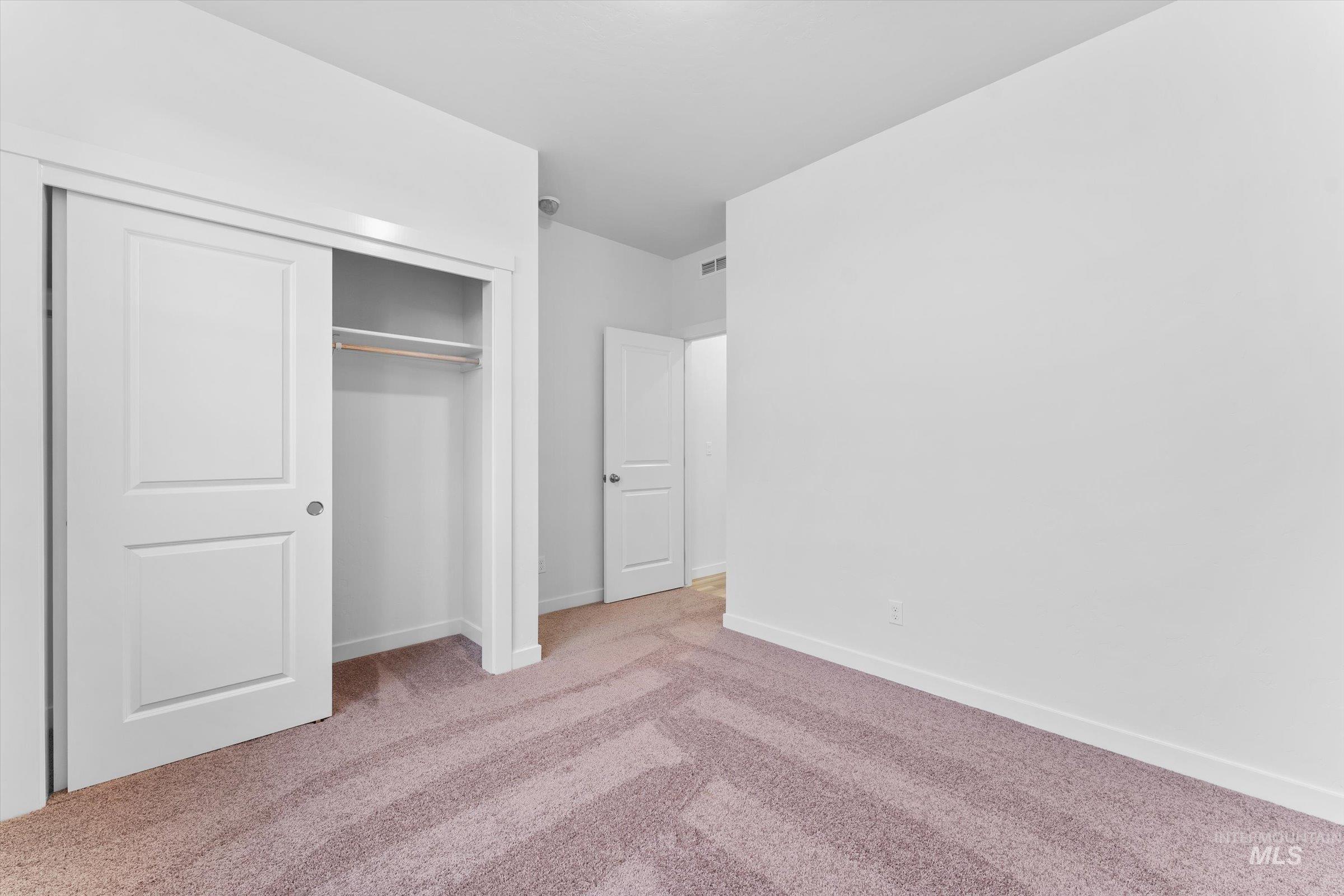 Unfurnished bedroom with light colored carpet and a closet