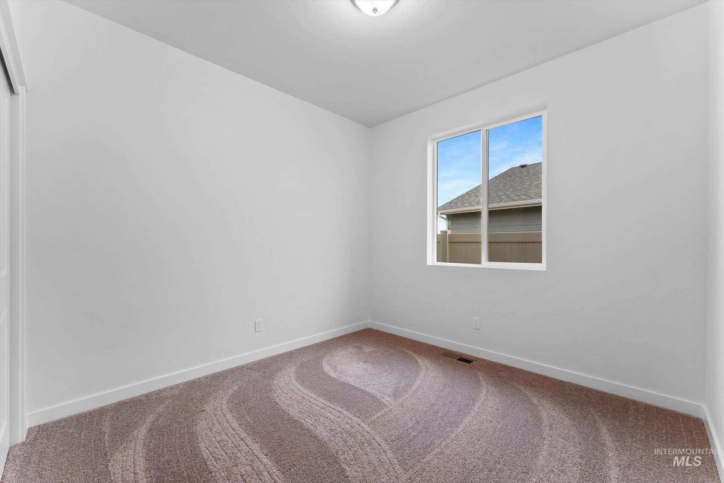 Carpeted empty room featuring baseboards