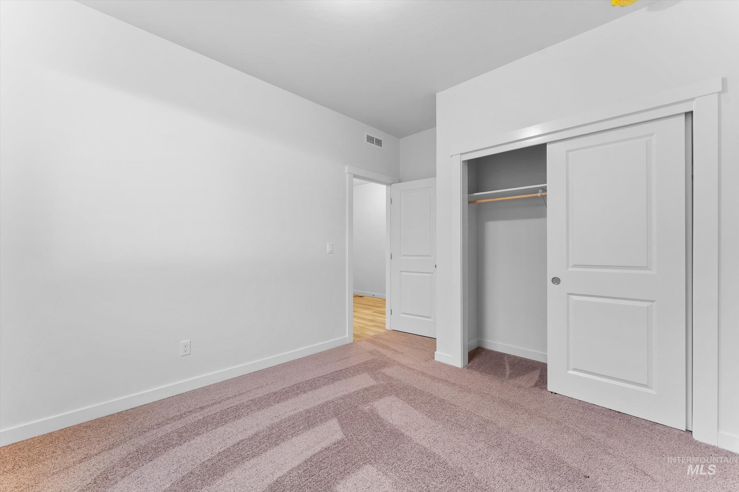 Unfurnished bedroom featuring light colored carpet and a closet