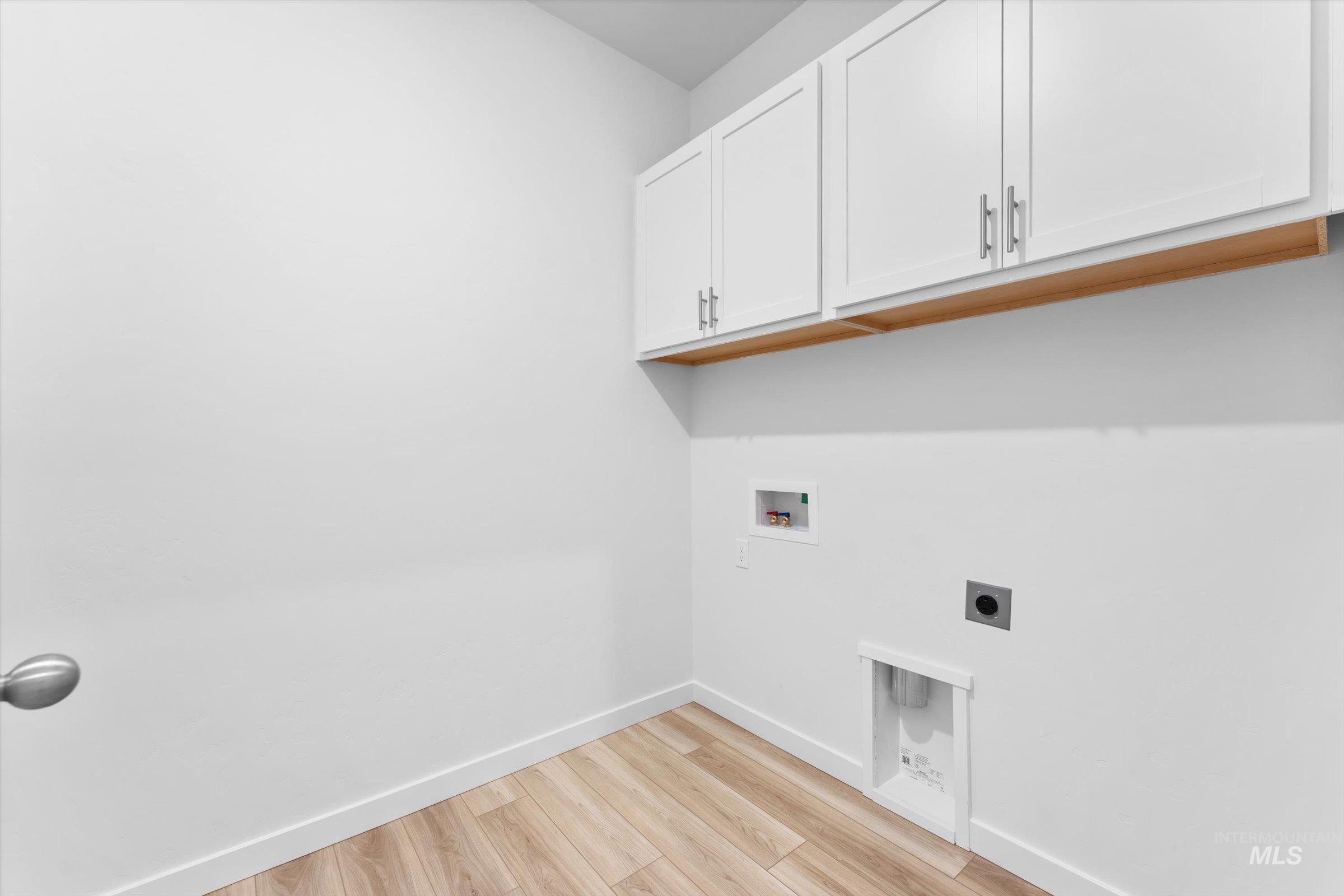 Laundry room with light wood-style floors, electric dryer hookup, cabinet space, and washer hookup