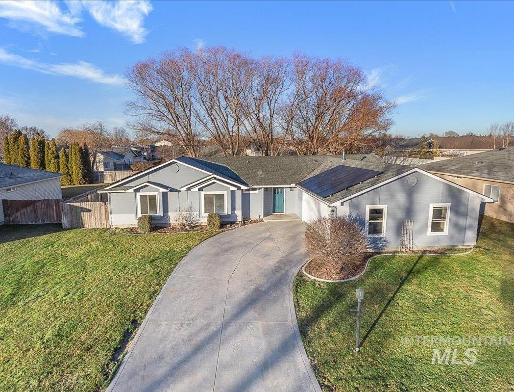 Ranch-style house featuring concrete driveway and solar panels
