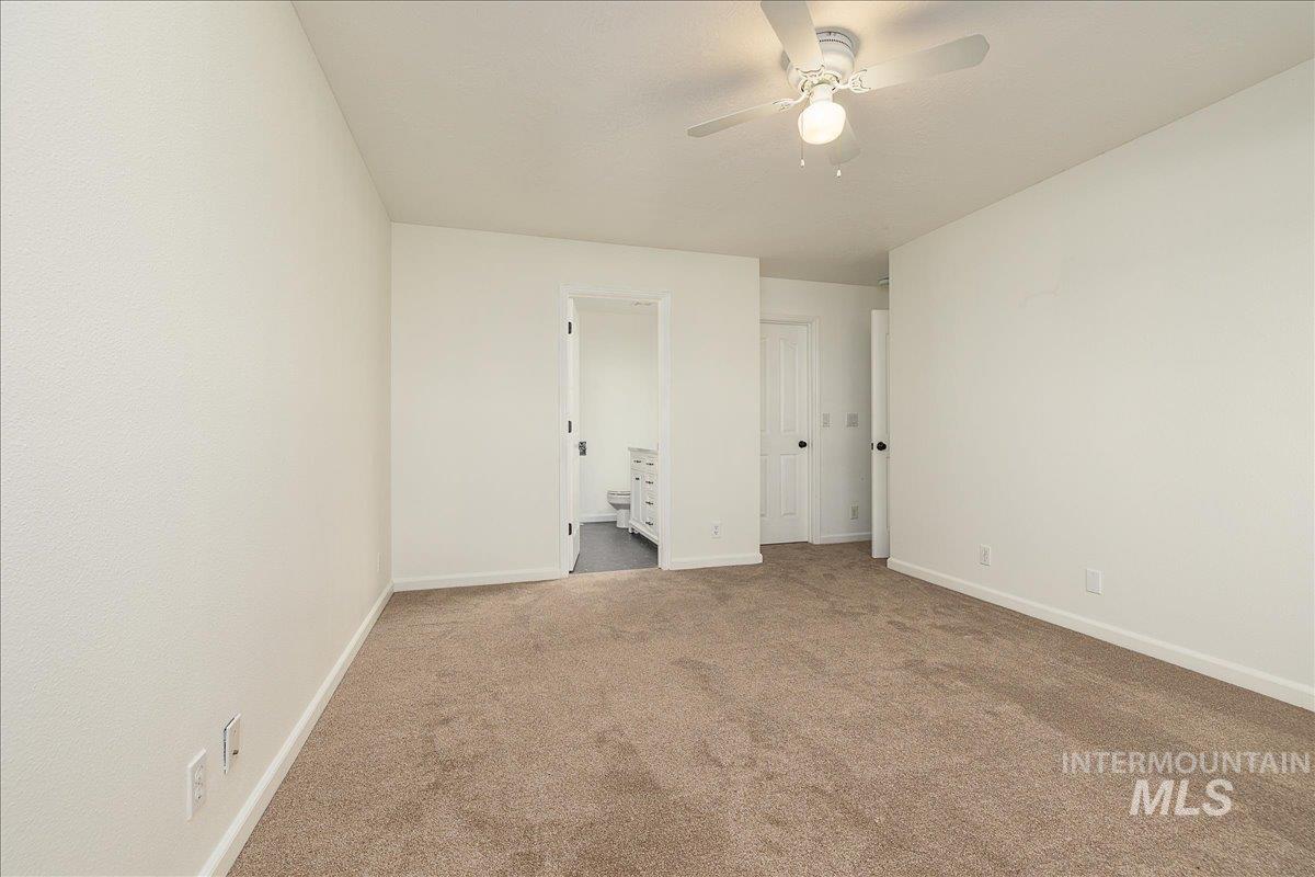 Unfurnished bedroom with carpet floors, ensuite bath, and ceiling fan