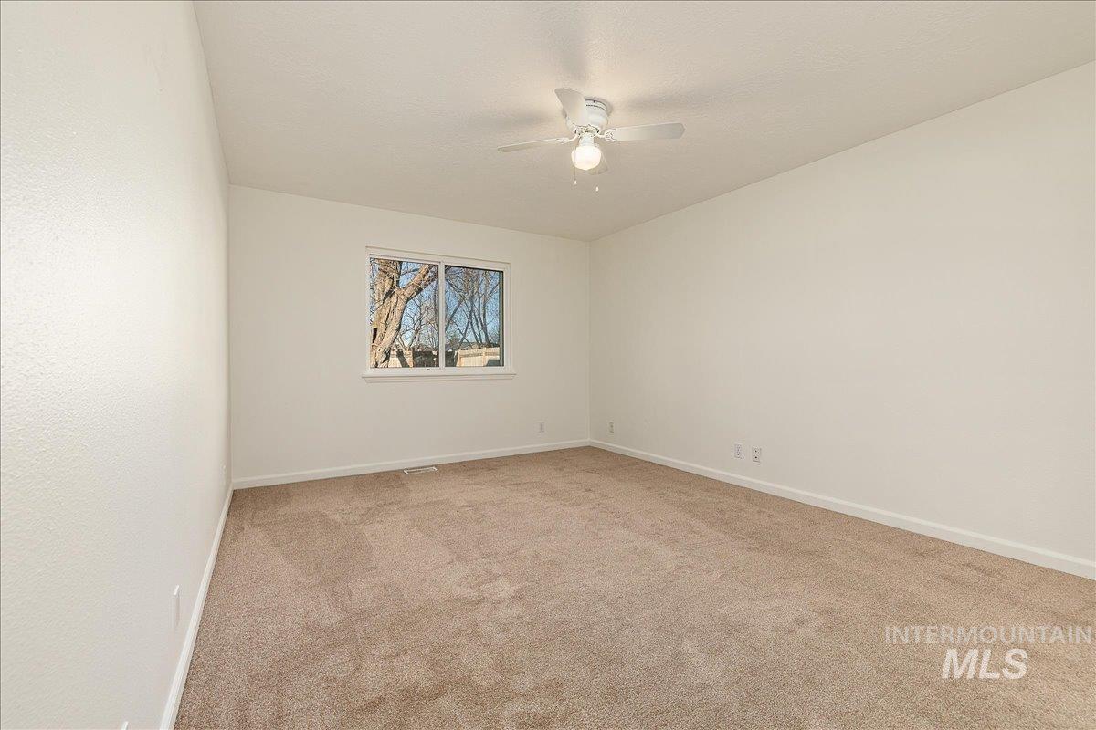 Empty room featuring light colored carpet and ceiling fan