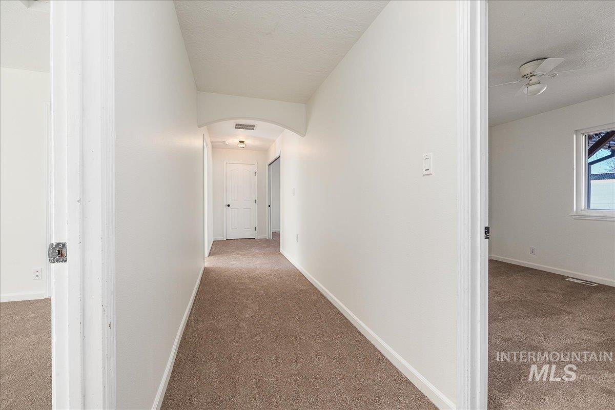 Hall featuring carpet, arched walkways, and a textured ceiling