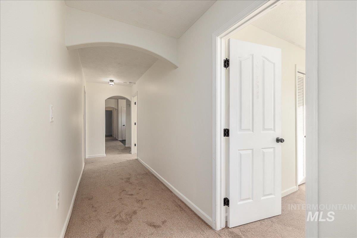 Corridor featuring light colored carpet and arched walkways