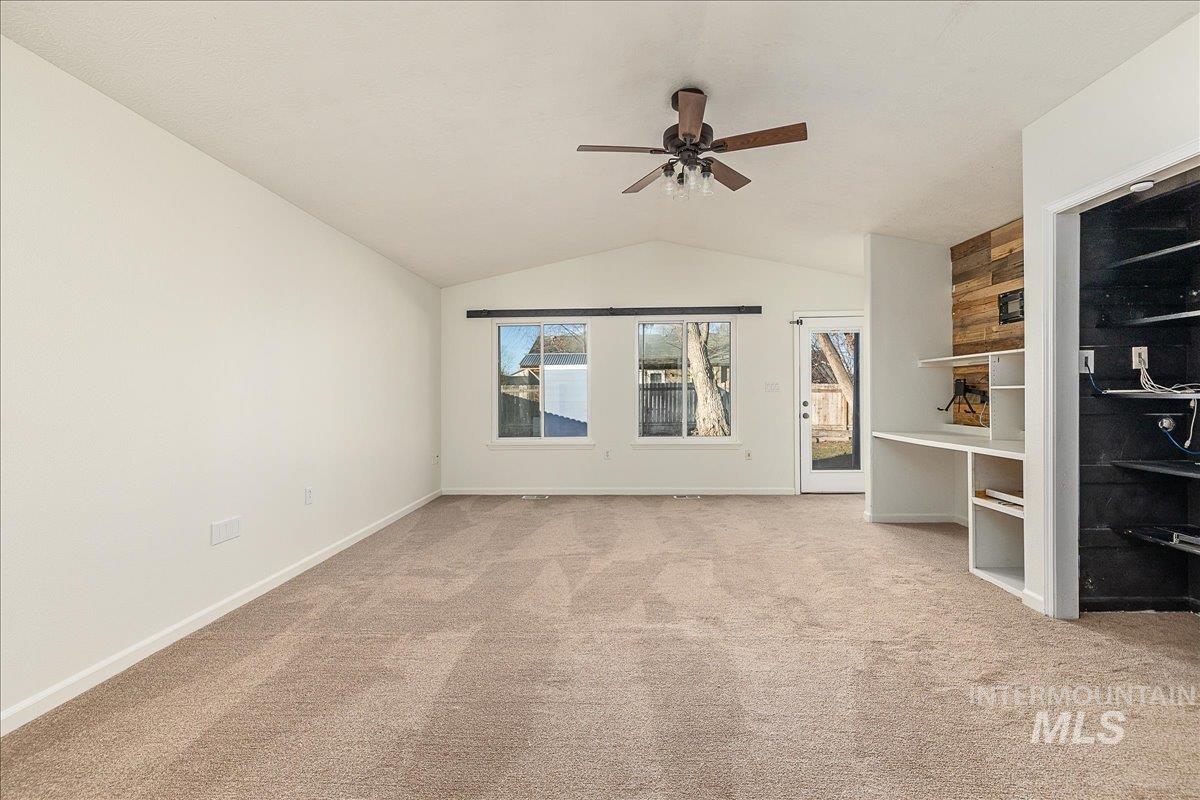 Unfurnished living room featuring lofted ceiling, light colored carpet, and ceiling fan